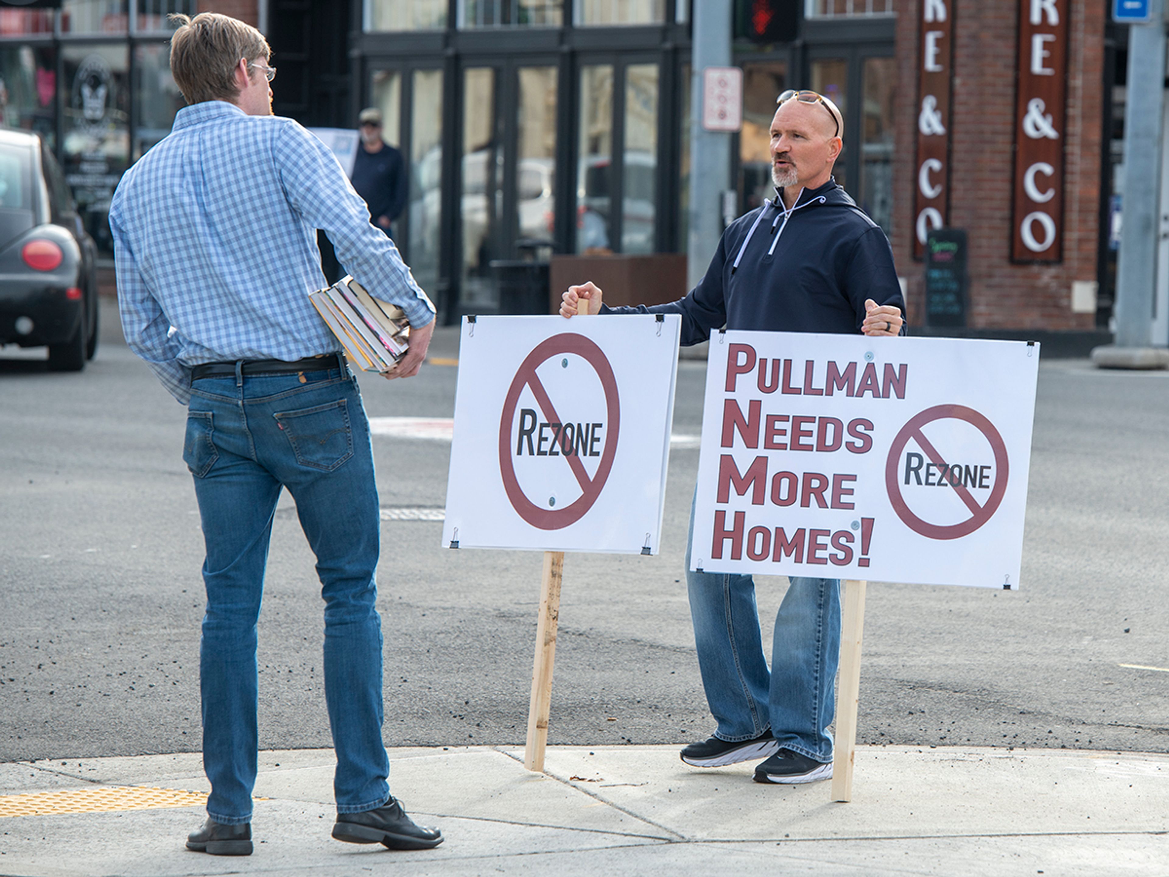 Passerby Geoff Riley, left, speaks with Gerry Eickhoff during a protest in downtown Pullman Monday against the Port of Whitman’s decision to rezone on a residential property next to Whispering Hills neighborhood.