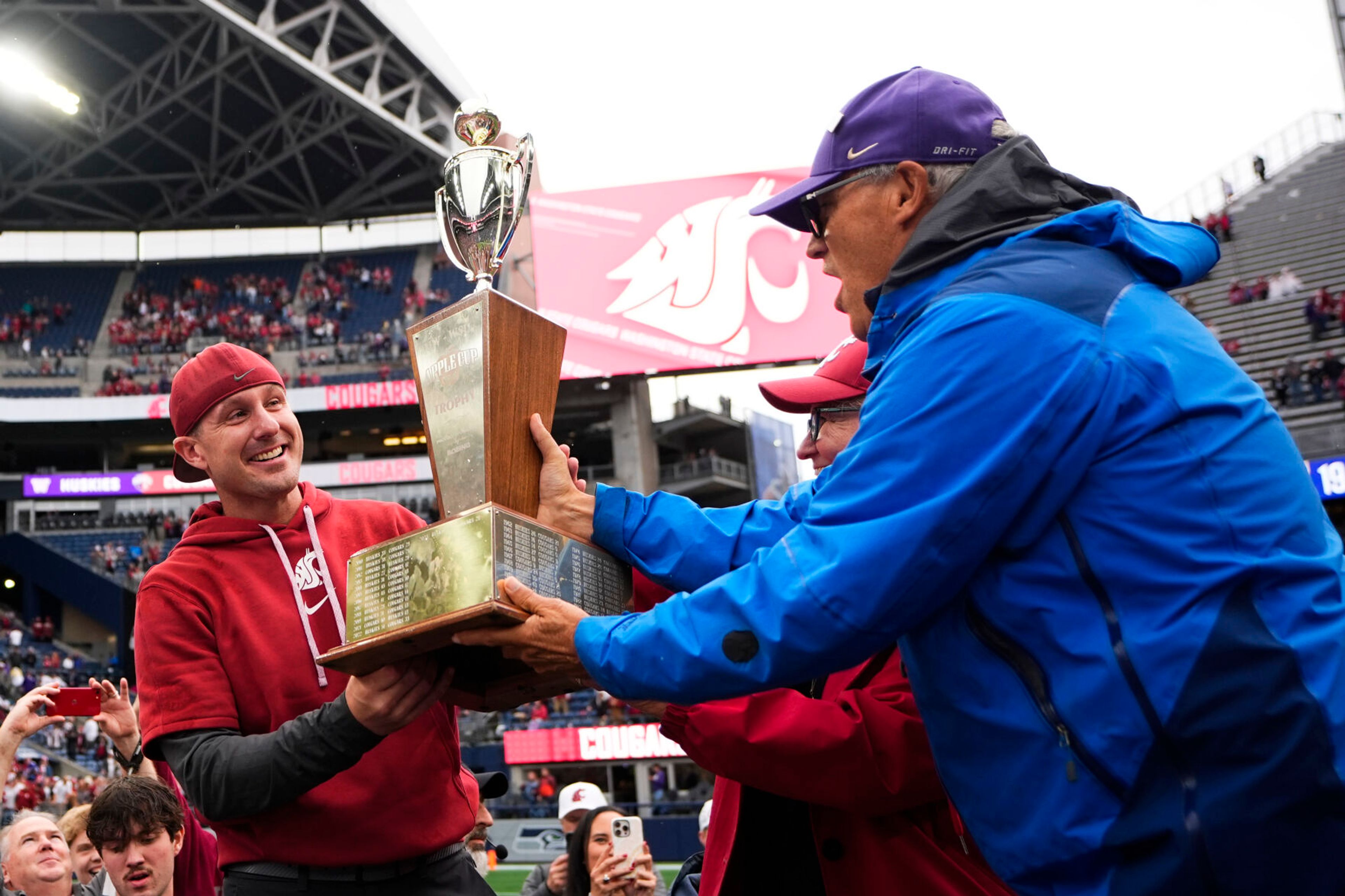 Washington State head coach Jake Dickert is handed the Apple Cup trophy by Governor Jay Inslee, right, and wife Trudi Inslee, center, after beating Washington 24-19 in an NCAA college football game Saturday, Sept. 14, 2024, in Seattle. (AP Photo/Lindsey Wasson)