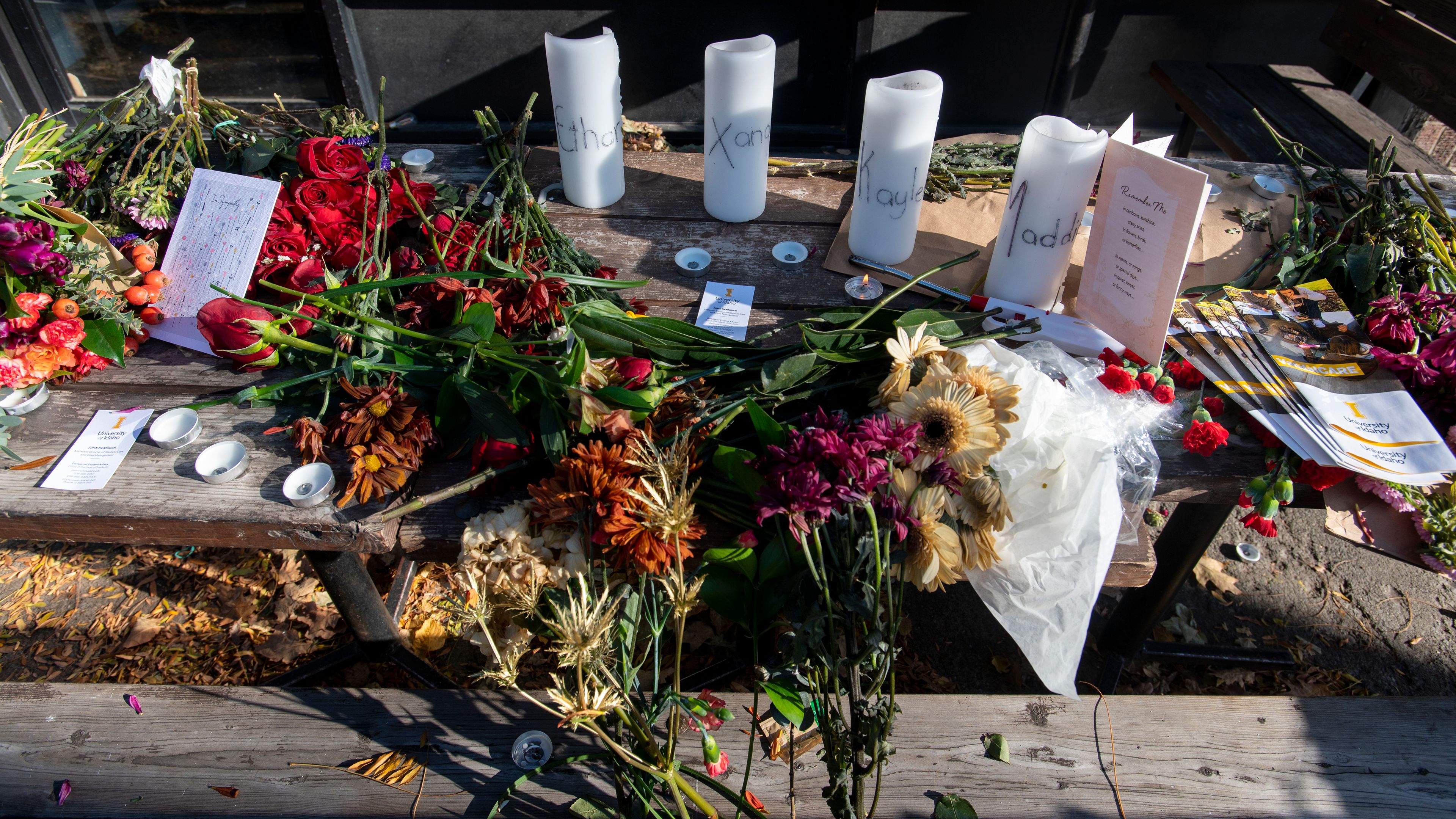 Candles and flowers rest on a table in honor of four deceased University of Idaho students, including Madison Mogen and Xana Kernodle, who worked at Mad Greek in downtown Moscow, at a memorial put together by coworkers outside of the restaurant on Tuesday.