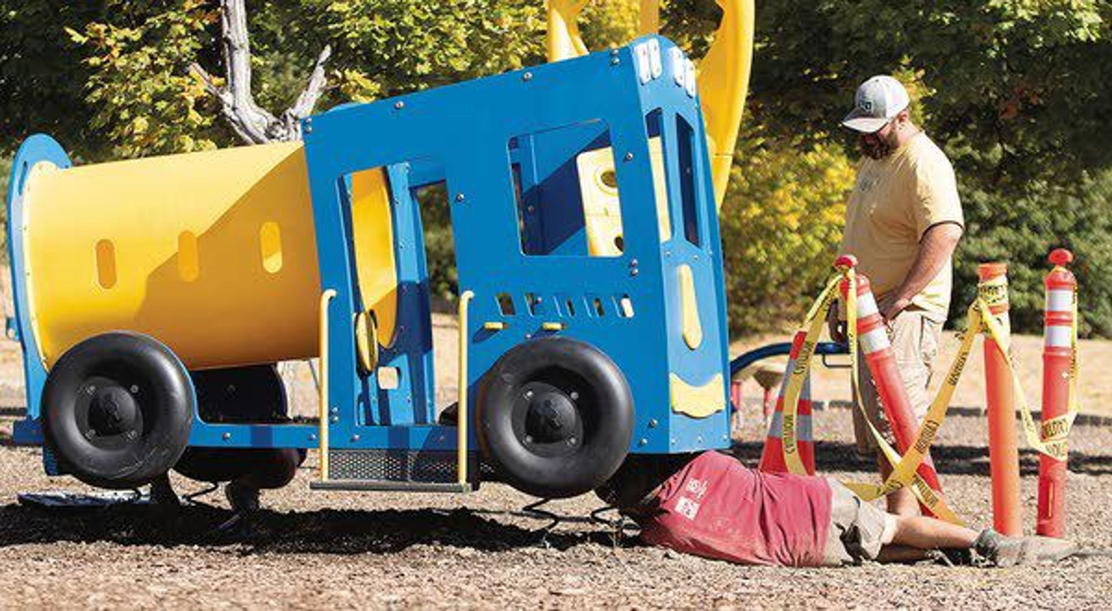 Jon Booker, bottom, and John Galbraith work to install a toy cement mixer Tuesday at Military Hill Park in Pullman. The toy was temporarily removed so graffiti could be removed from it.