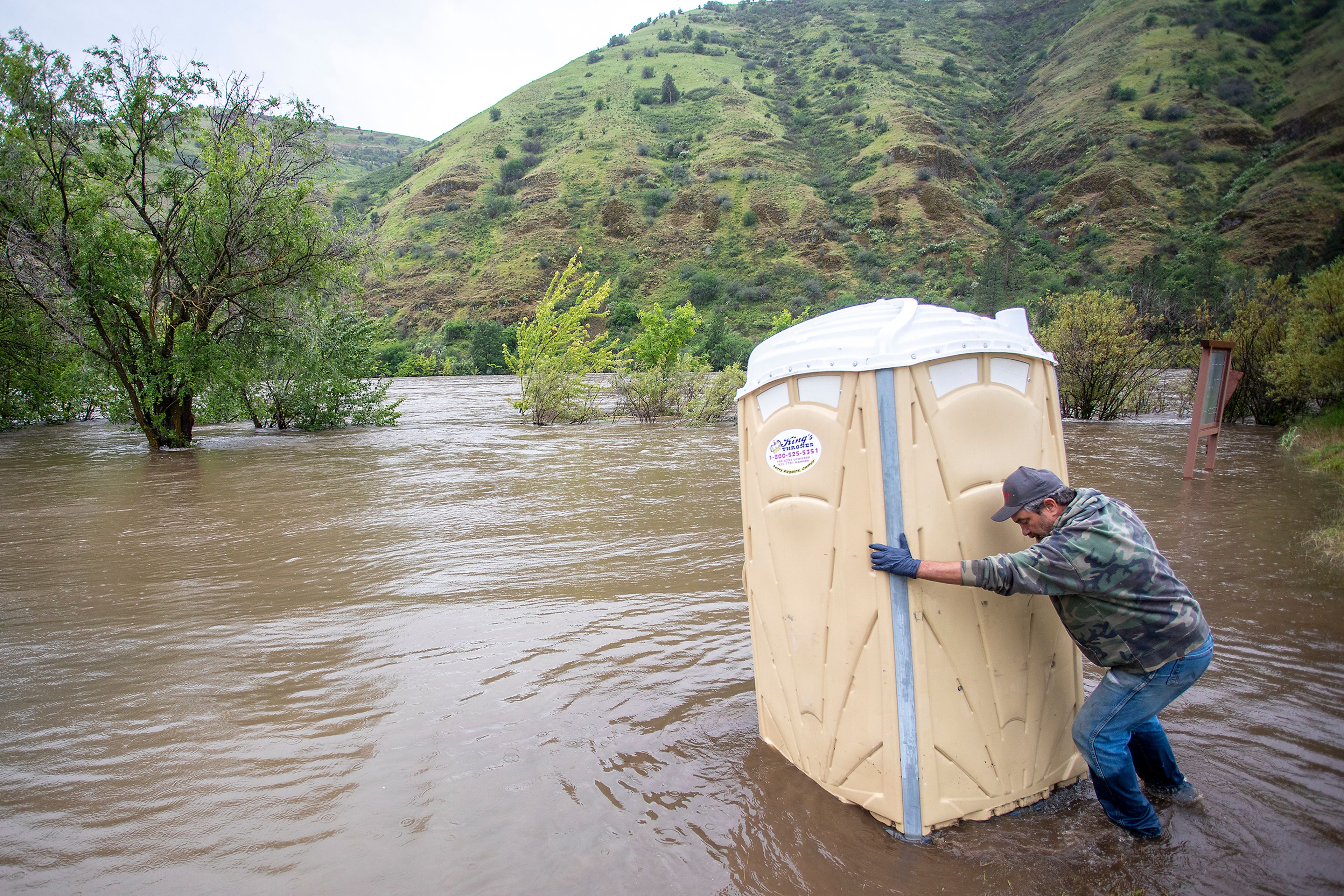 Jim Edmison works to pull a port-a-potty out of a flooded area from the Clearwater River at the end of Mullalley Road on Monday.