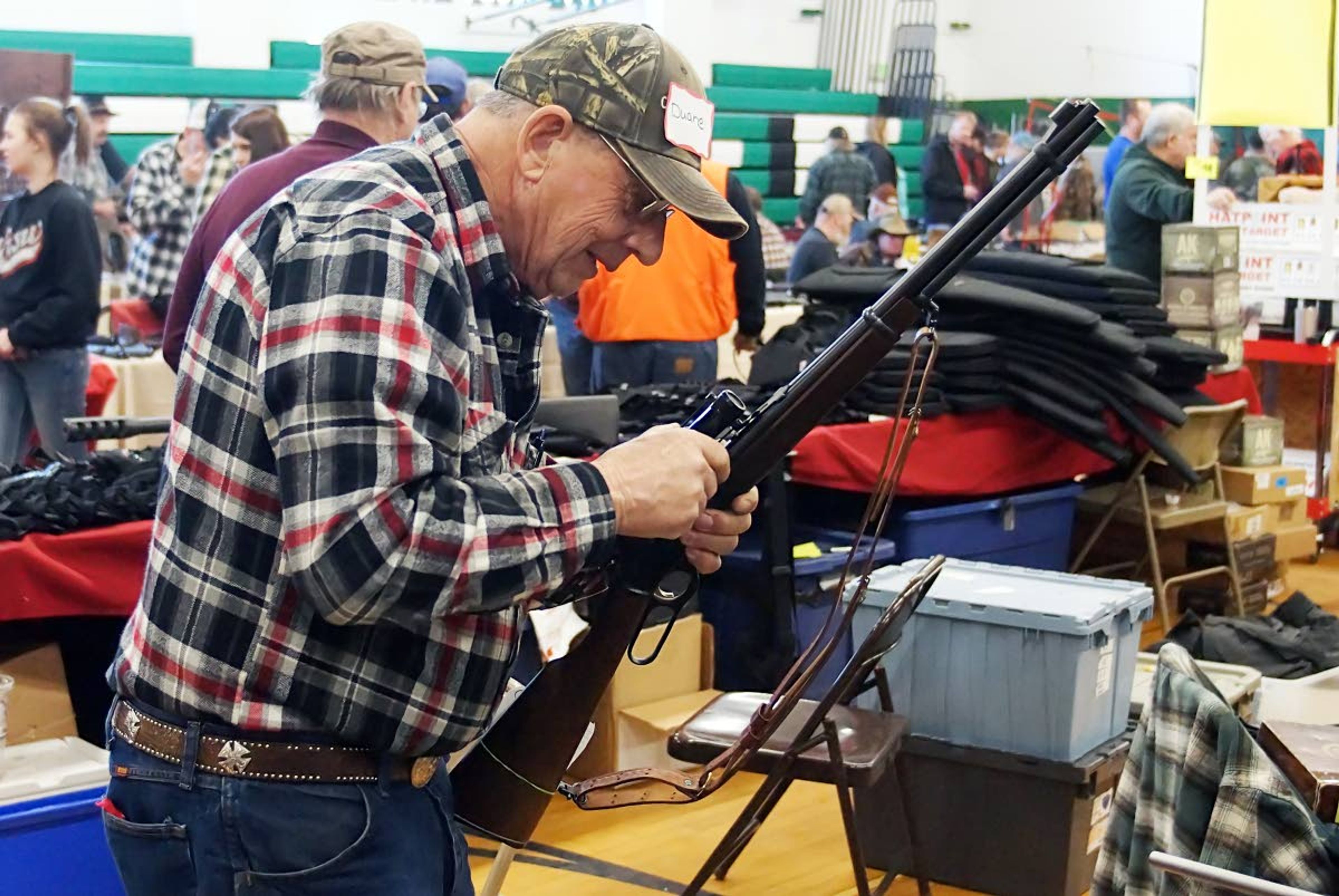 Potlatch Gun Show vendor Duane Owens removes a scope from a Marlin 30-30 Sunday afternoon.