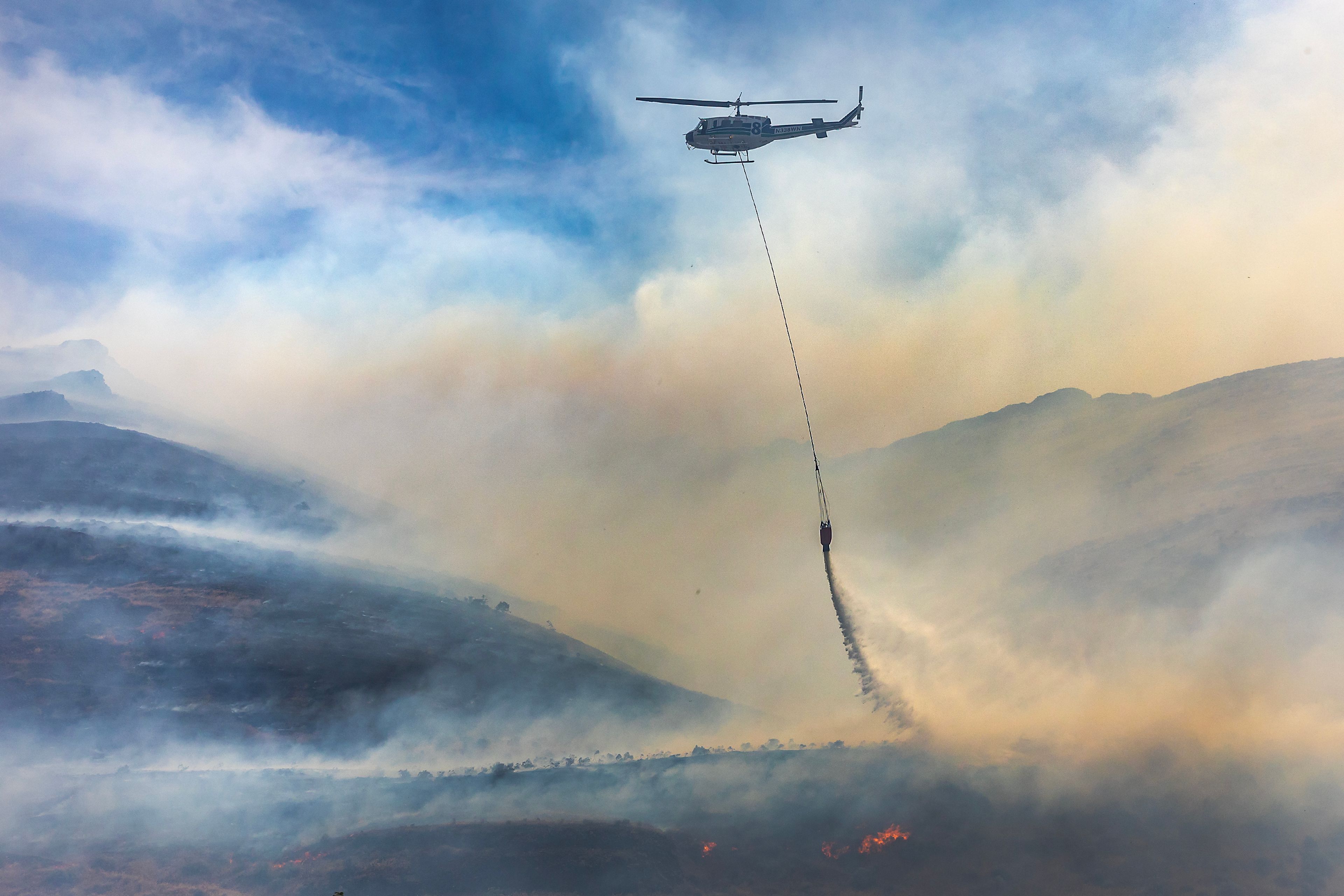 A helicopter makes a drop on a fire moving along the hillside by Nisqually John Landing off of Wawawai Road on Friday.