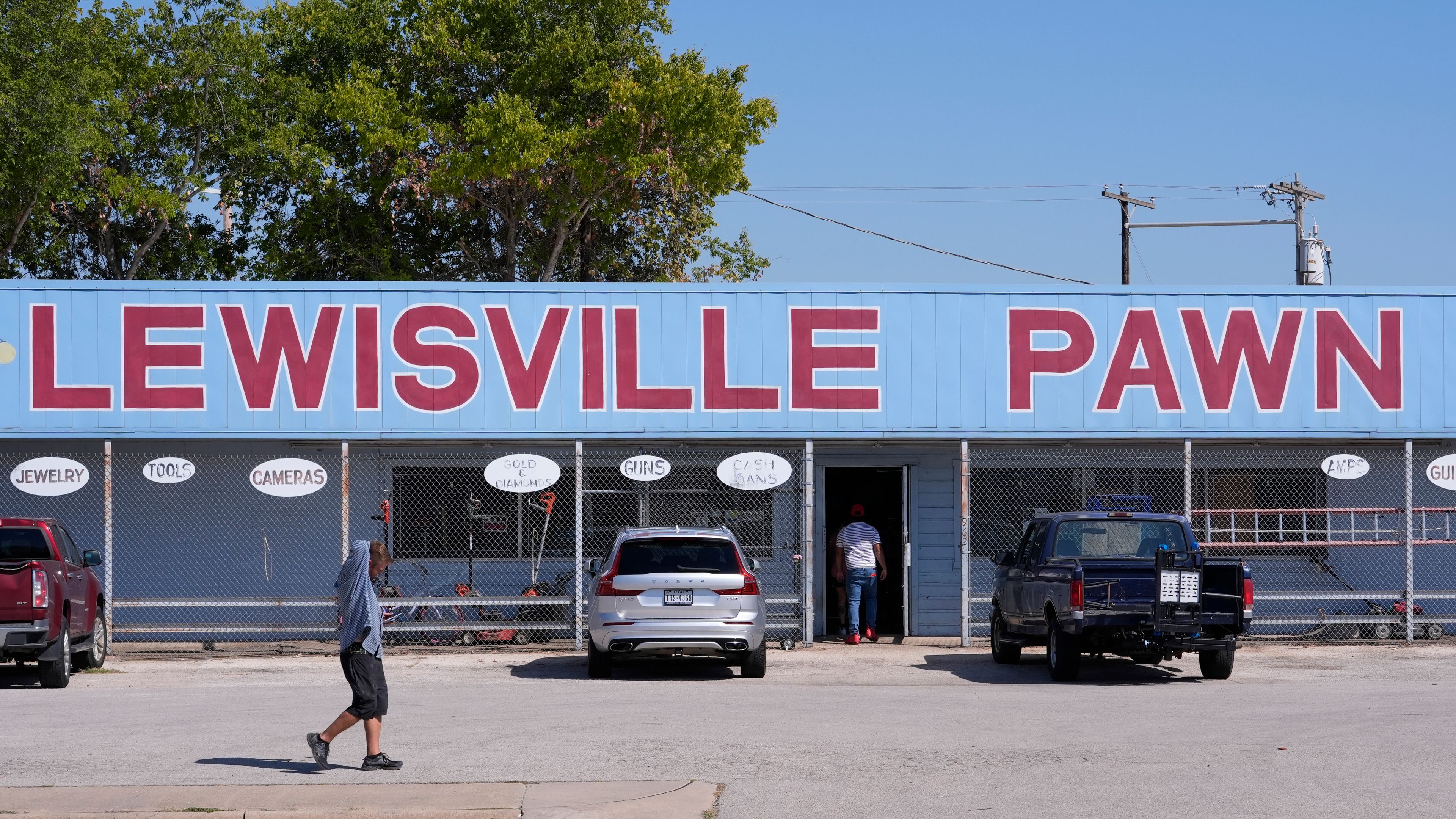 People walk and enter a business in Lewisville, Texas, Friday, Oct. 4, 2024. (AP Photo/LM Otero)