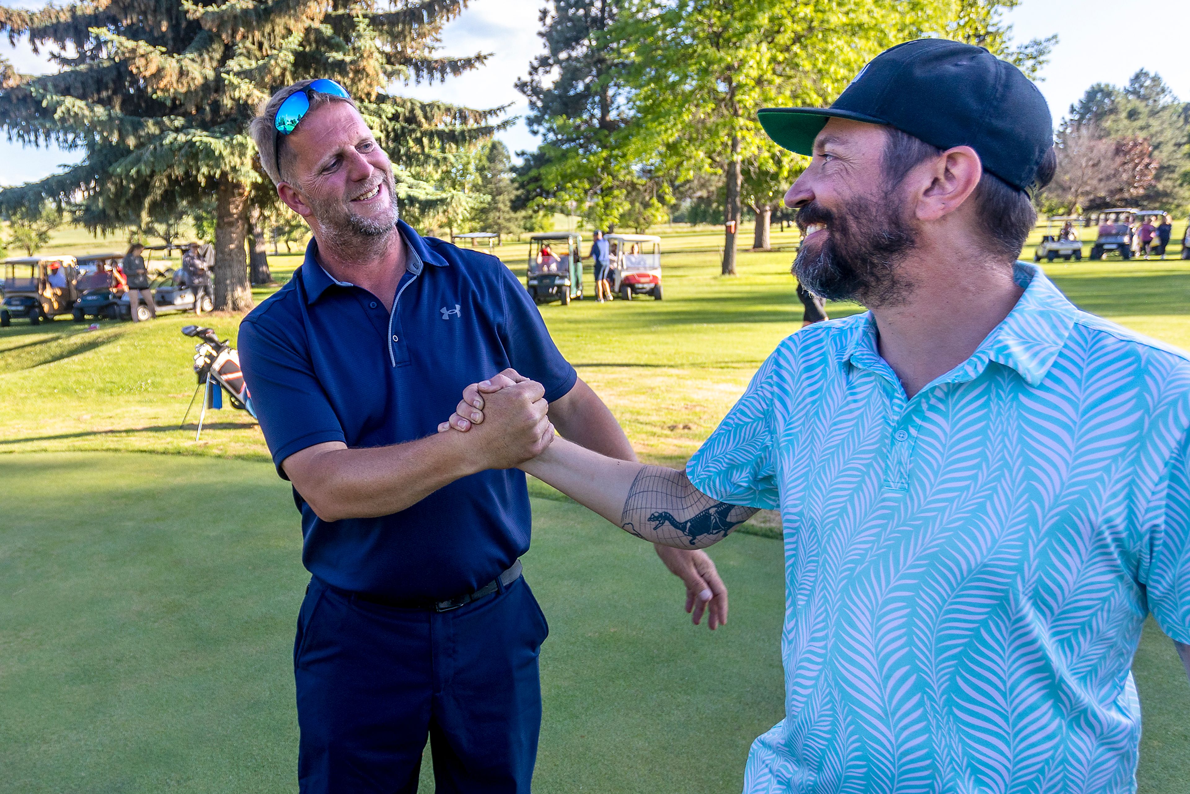 Sean Dorigo, left, grasps hands with Thad Froio after winning the Moscow Sole Survivor golf tournament on July 4, 2022.