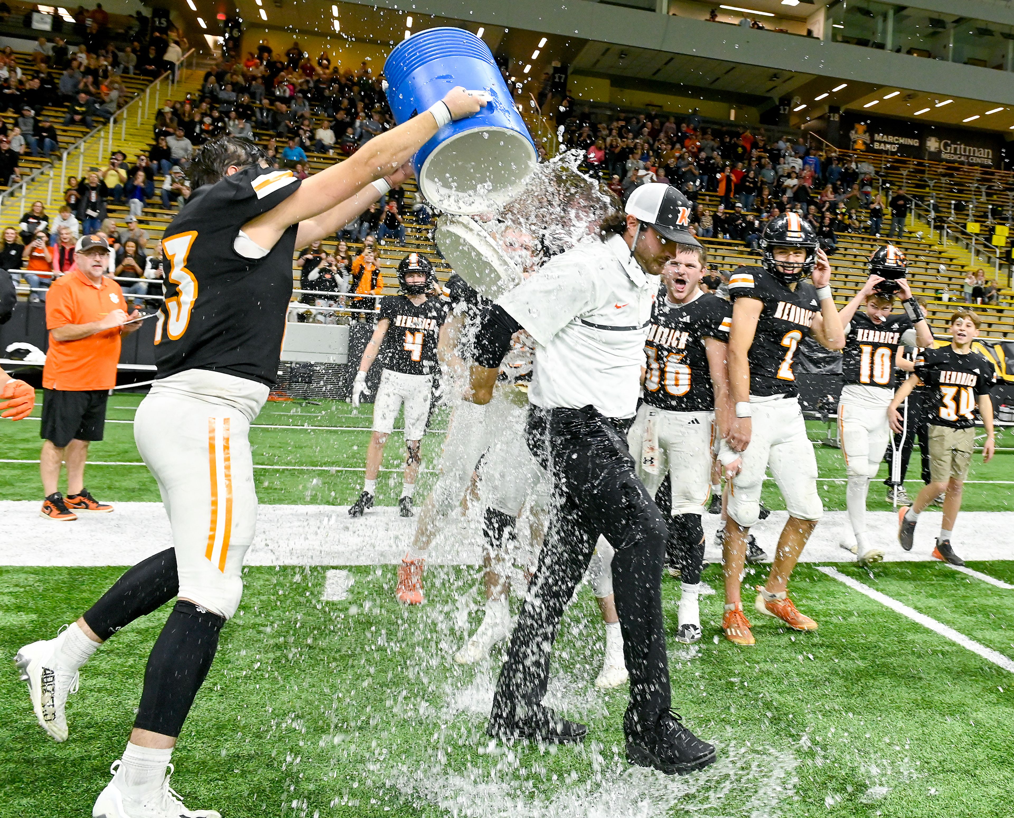 A cooler is dumped over Kendrick head coach Zane Hobart as the team celebrates its win over Butte County to claim the Idaho 2A state championship Friday at the P1FCU Kibbie Dome in Moscow.