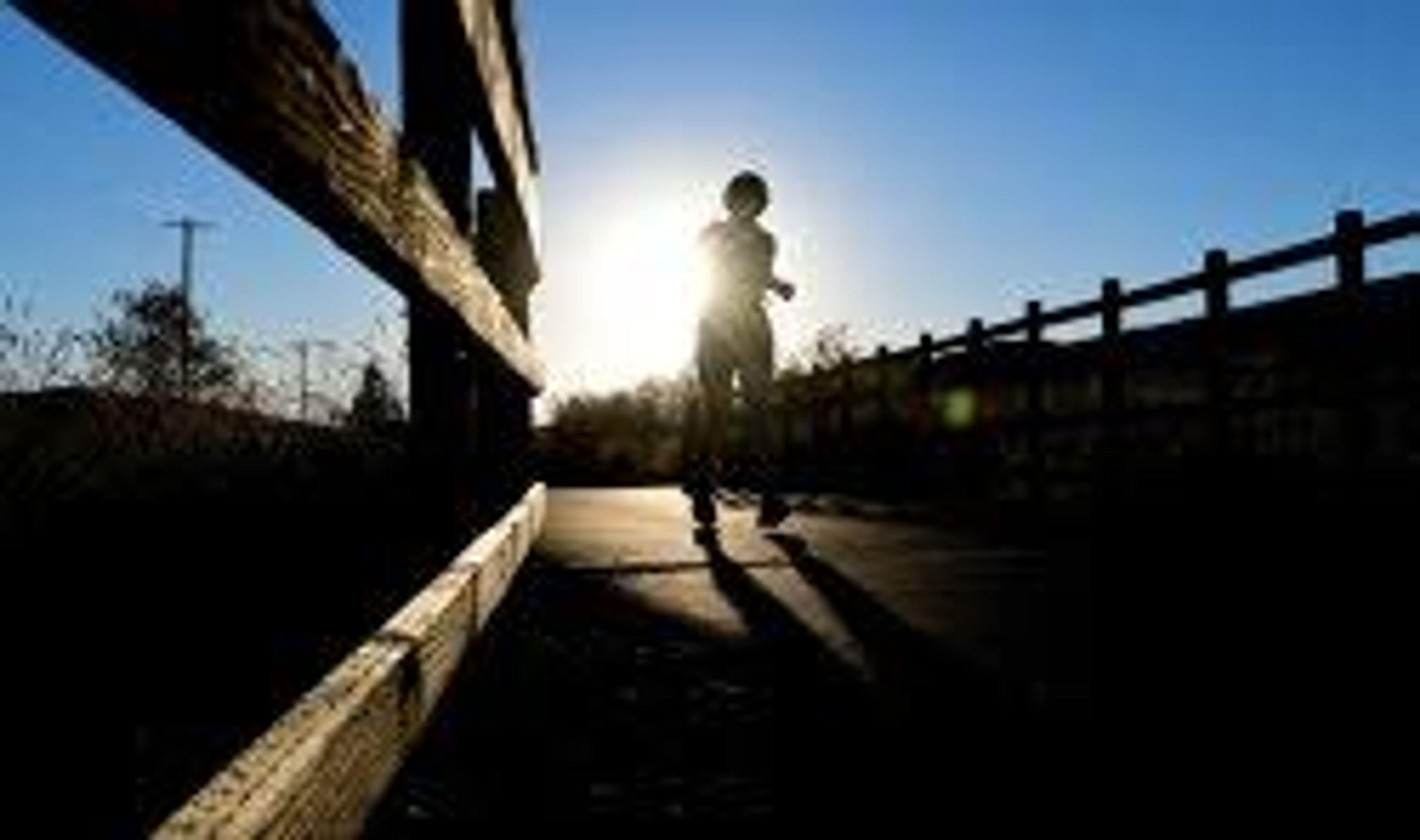 The sun turns a runner crossing a bridge into a silhouette along the Bill Chipman Palouse Trail in Pullman.