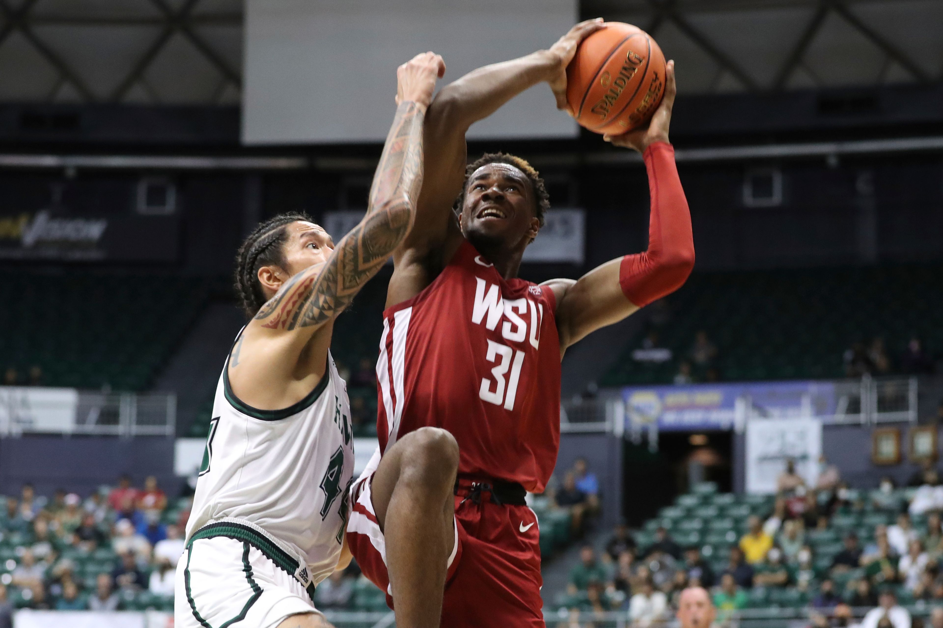 Washington State guard Kymany Houinsou (31) shoots next to Hawaii forward Kamaka Hepa (44) during the first half of an NCAA college basketball game Friday, Dec. 23, 2022, in Honolulu. (AP Photo/Marco Garcia)