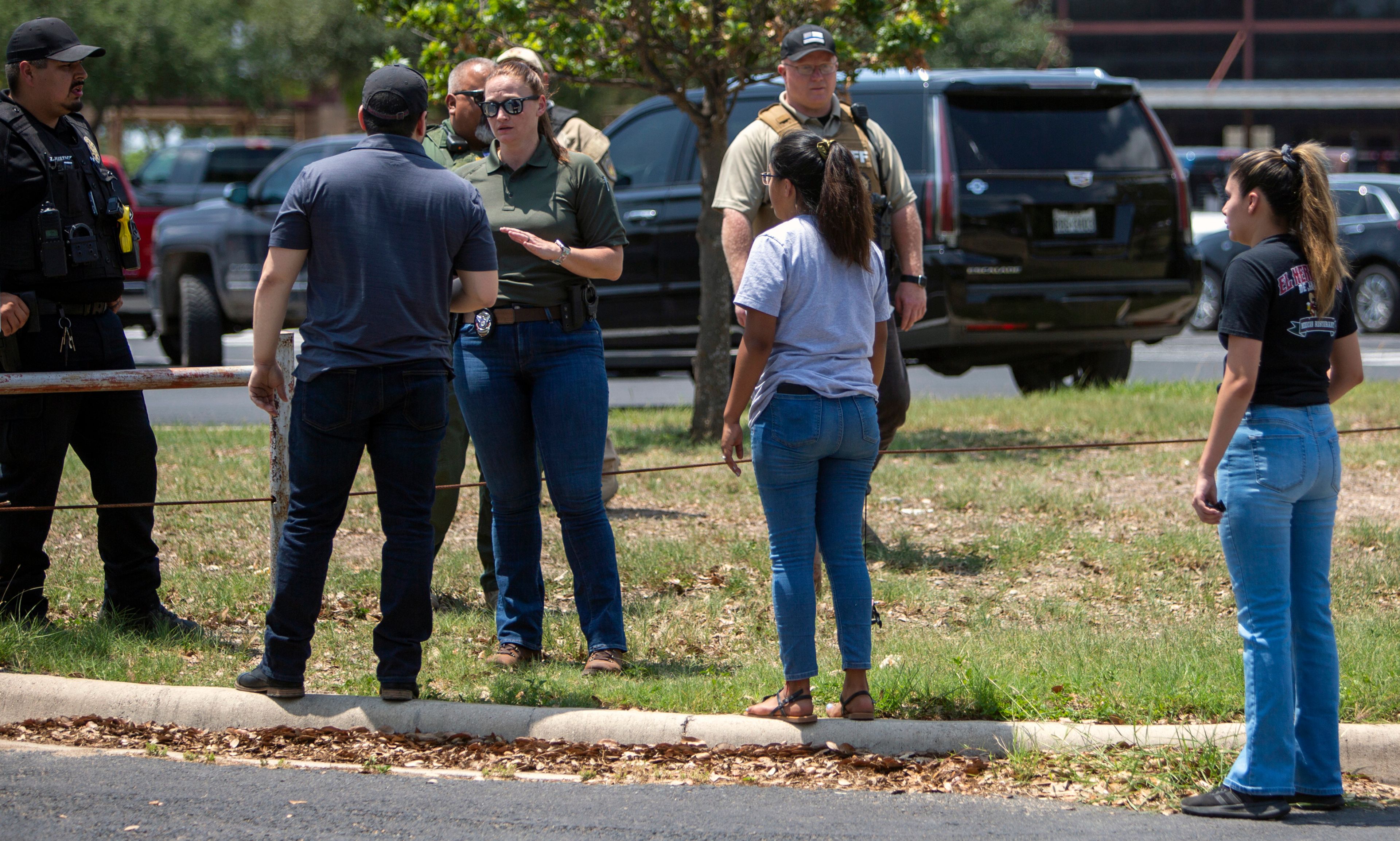 A law enforcement officer speaks with people outside Uvalde High School after shooting a was reported earlier in the day at Robb Elementary School, Tuesday, May 24, 2022, in Uvalde, Texas. (William Luther/The San Antonio Express-News via AP)