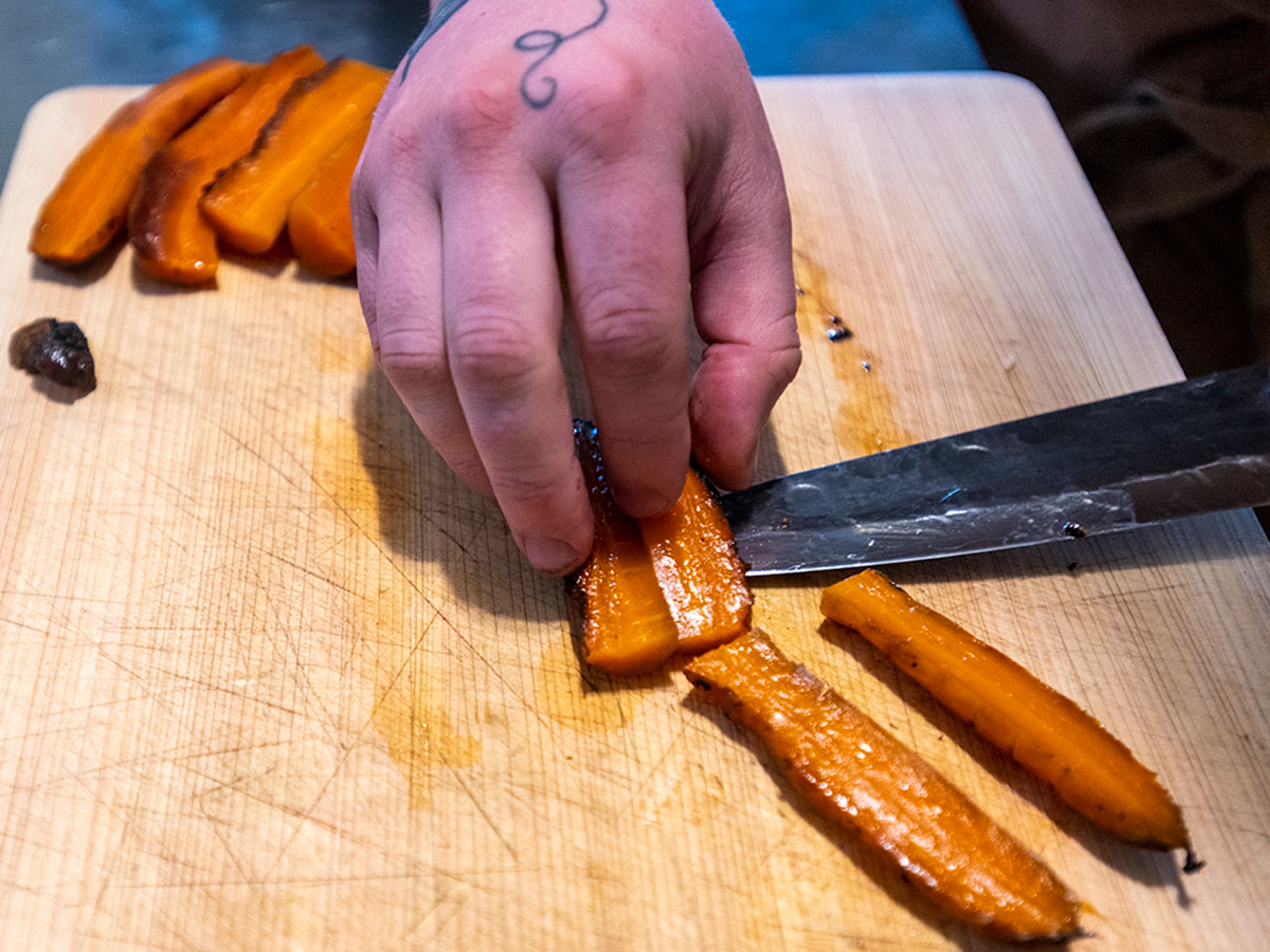 Pecoraro slices beef fat roasted Ronnigers farms carrots while preparing a typical Cellar Door Cooking dish.