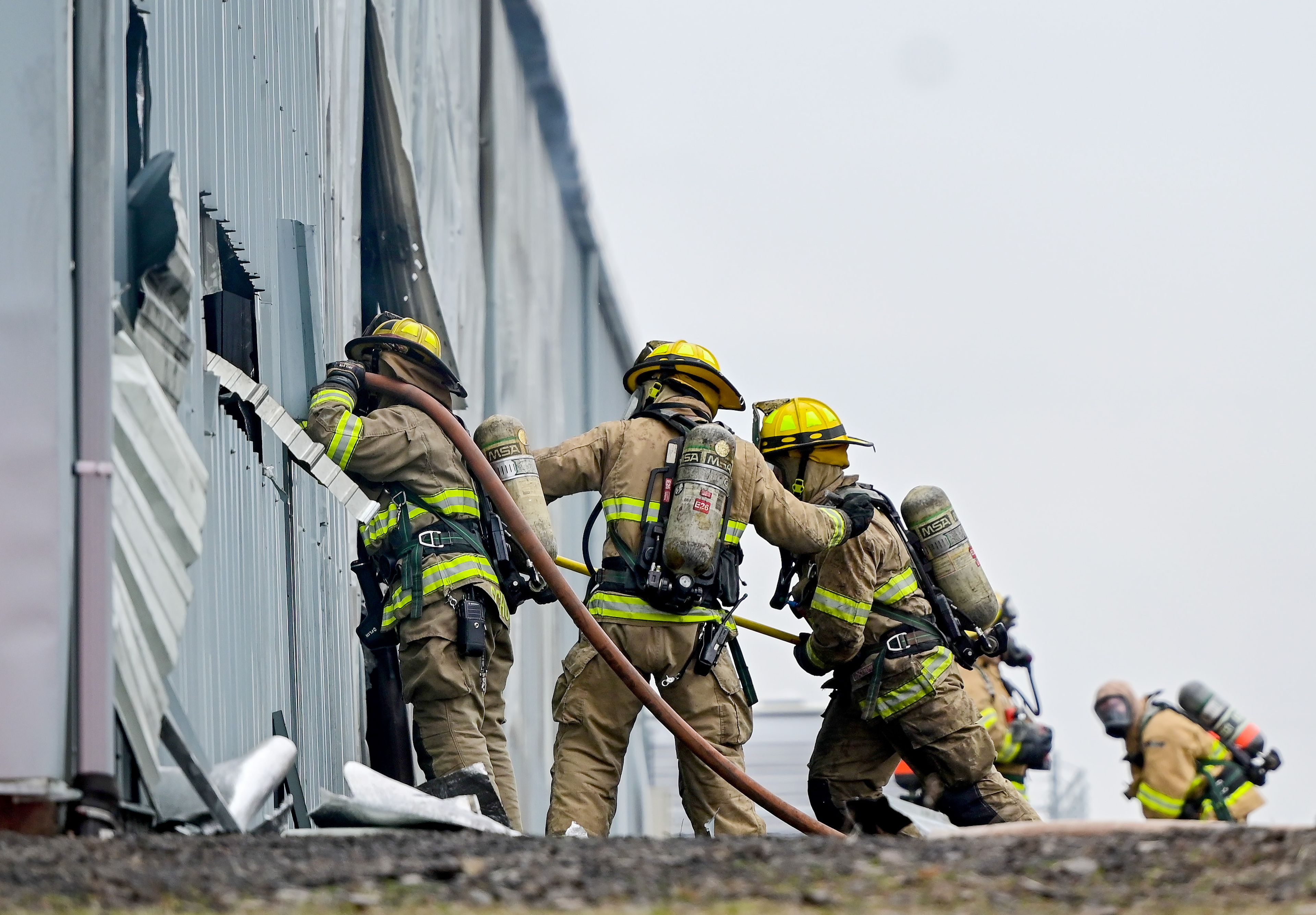 Fire crews raise hoses to holes cut into the side of units at Express Storage in the aftermath of the large fire along Moscow-Pullman Highway on Thursday.