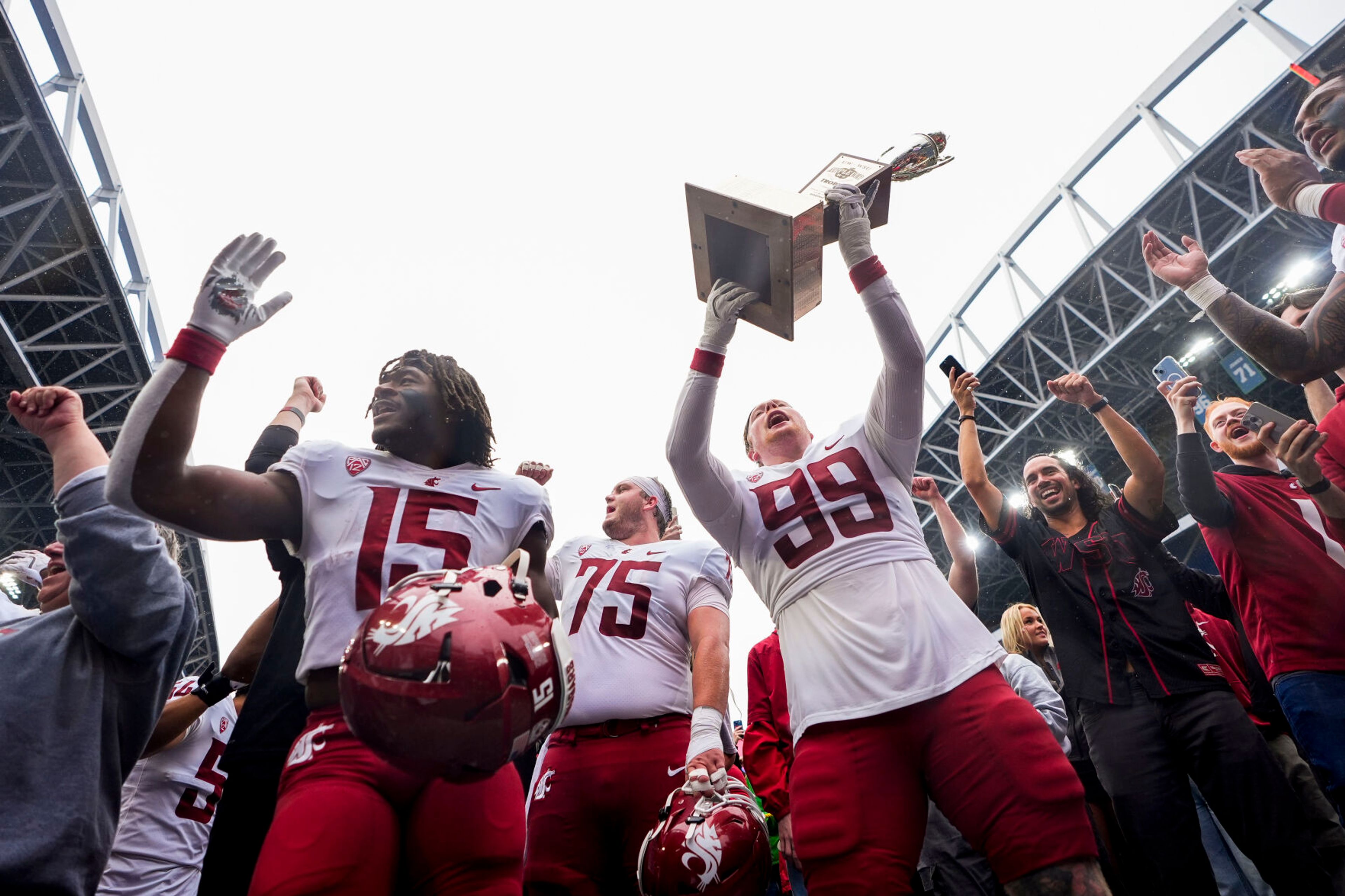 Washington State defensive tackle Bryson Lamb (99) holds up the Apple Cup Trophy while celebrating with offensive lineman Noah Dunham (75) and running back Djouvensky Schlenbaker (15) after beating Washington 24-19 in an NCAA college football game Saturday, Sept. 14, 2024, in Seattle. (AP Photo/Lindsey Wasson)