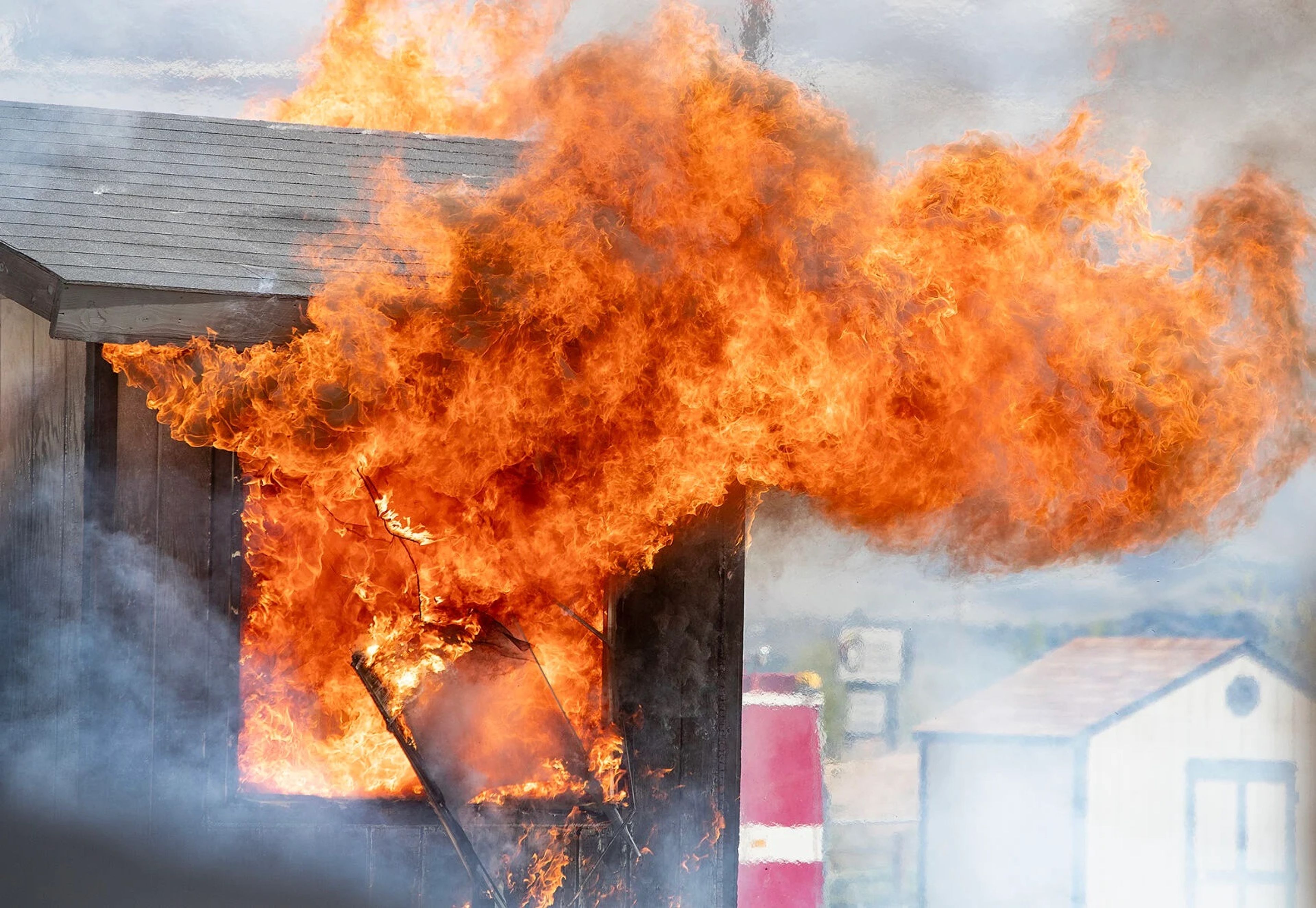 A window blows out as flames pour from inside a small building being consumed by fire during a demonstration at the National Interagency Fire Center on Monday in Boise.