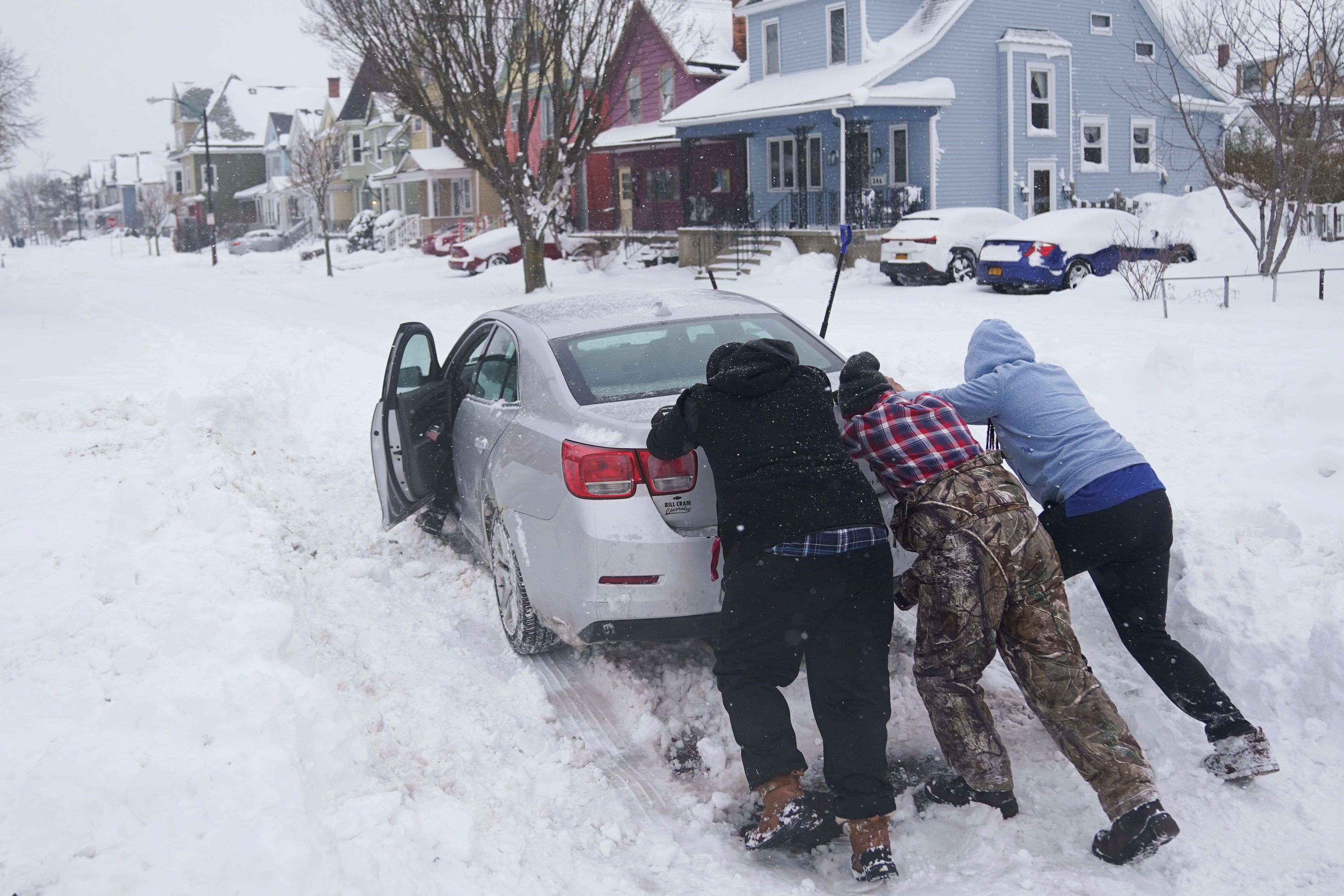 Neighbors help push a motorist stuck in the snow in Buffalo, N.Y., on Monday, Dec. 26, 2022. (Derek Gee/The Buffalo News via AP)