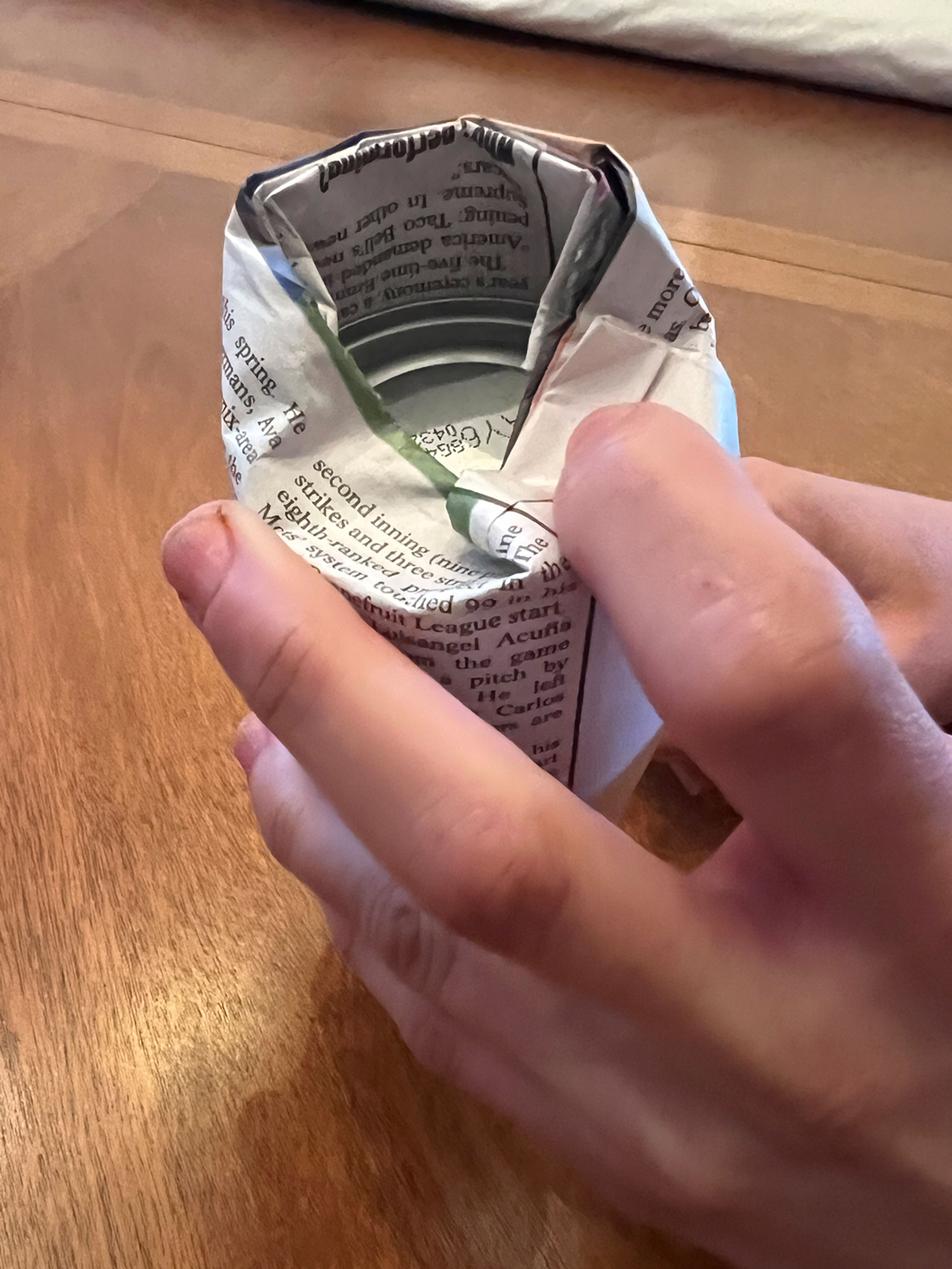 This March 2, 2025, image shows a step in making a DIY seed pot from a sheet of newspaper. (Jessica Damiano via AP)
