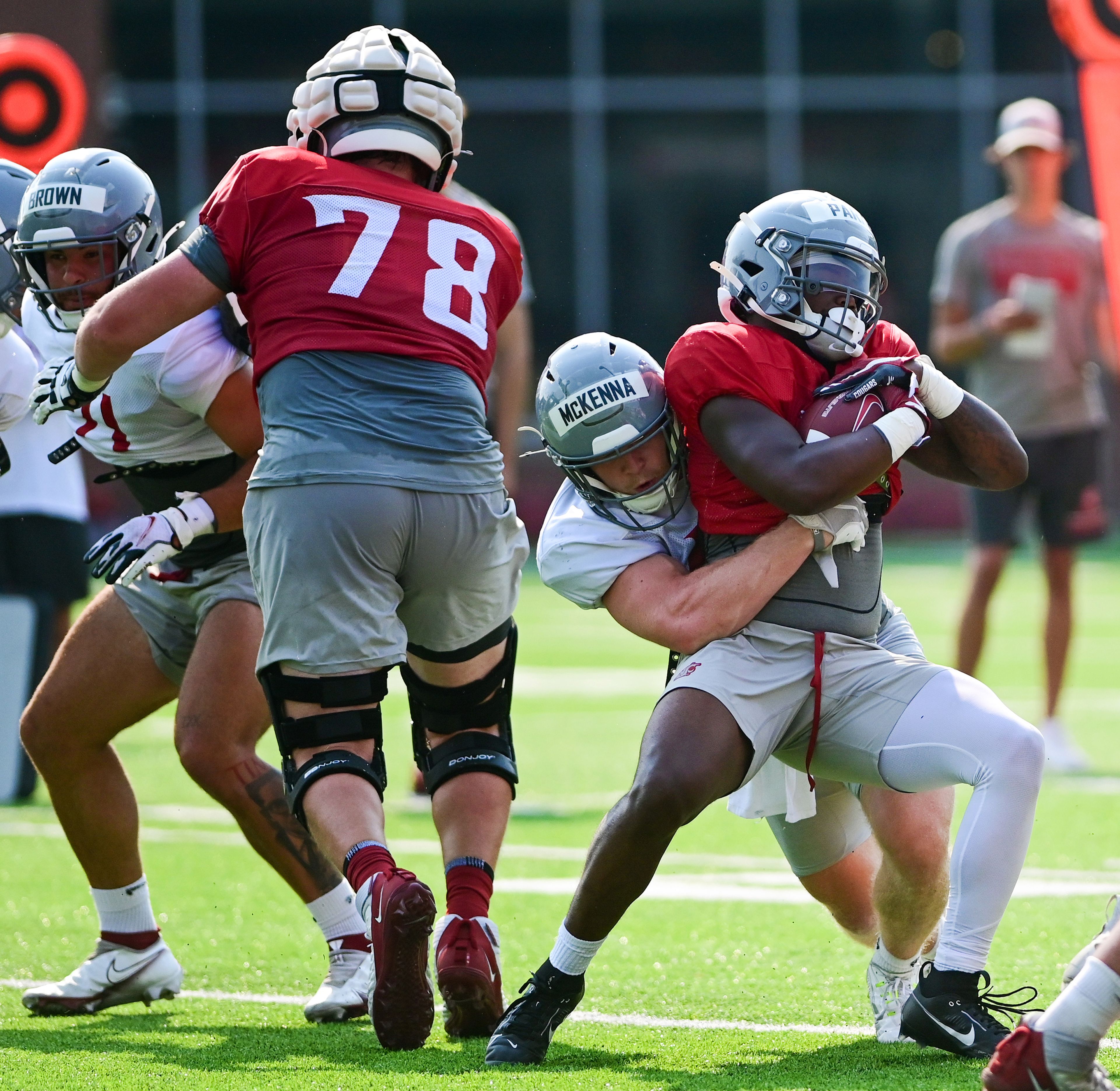 Washington State running back Wayshawn Parker holds onto the ball as linebacker Parker McKenna grabs hold at WSU’s fall camp on Friday in Pullman.