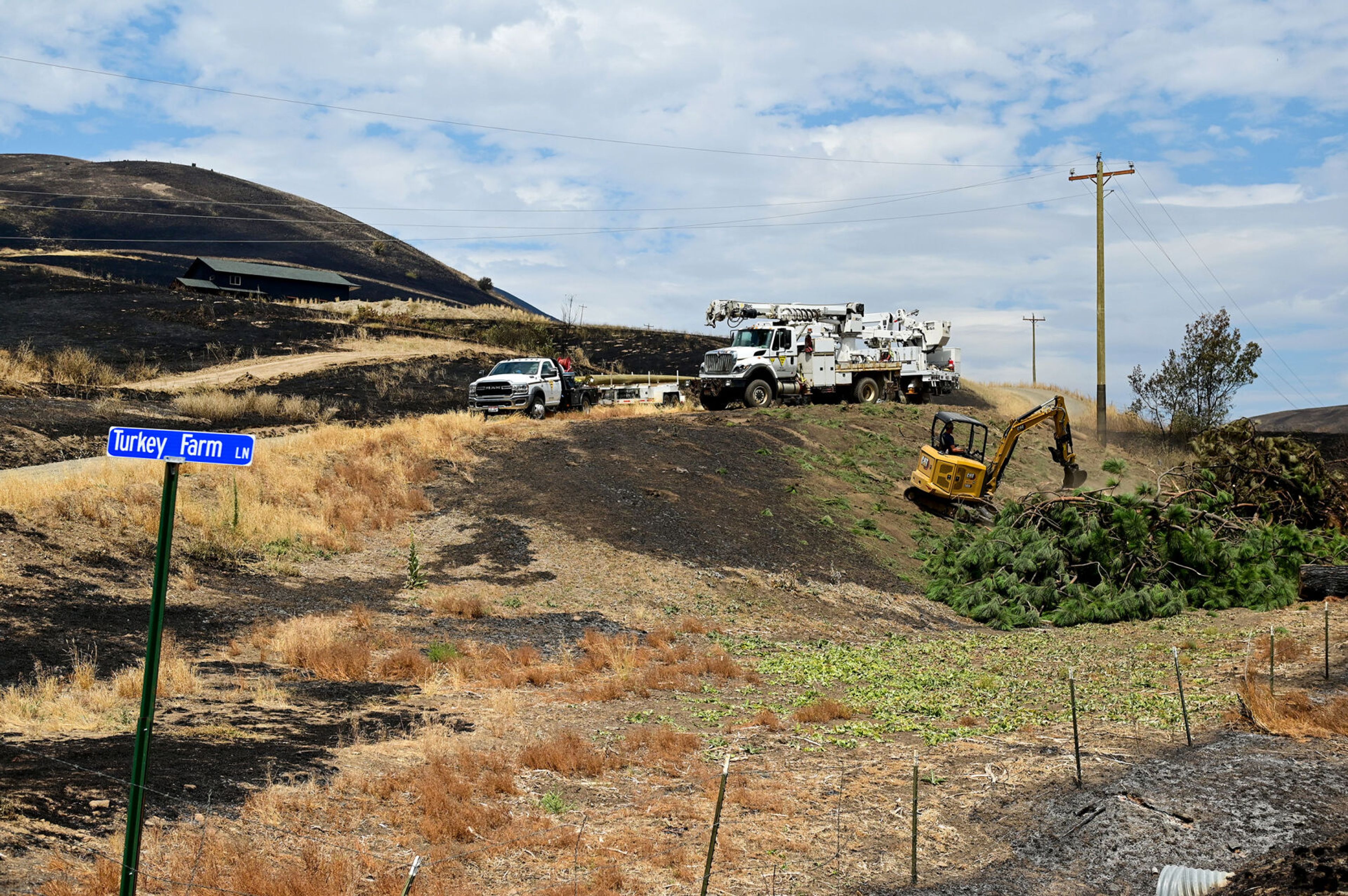 Crews work to clear debris and check on utility lines along Idaho Highway 3 on Monday after the Gwen Fire.