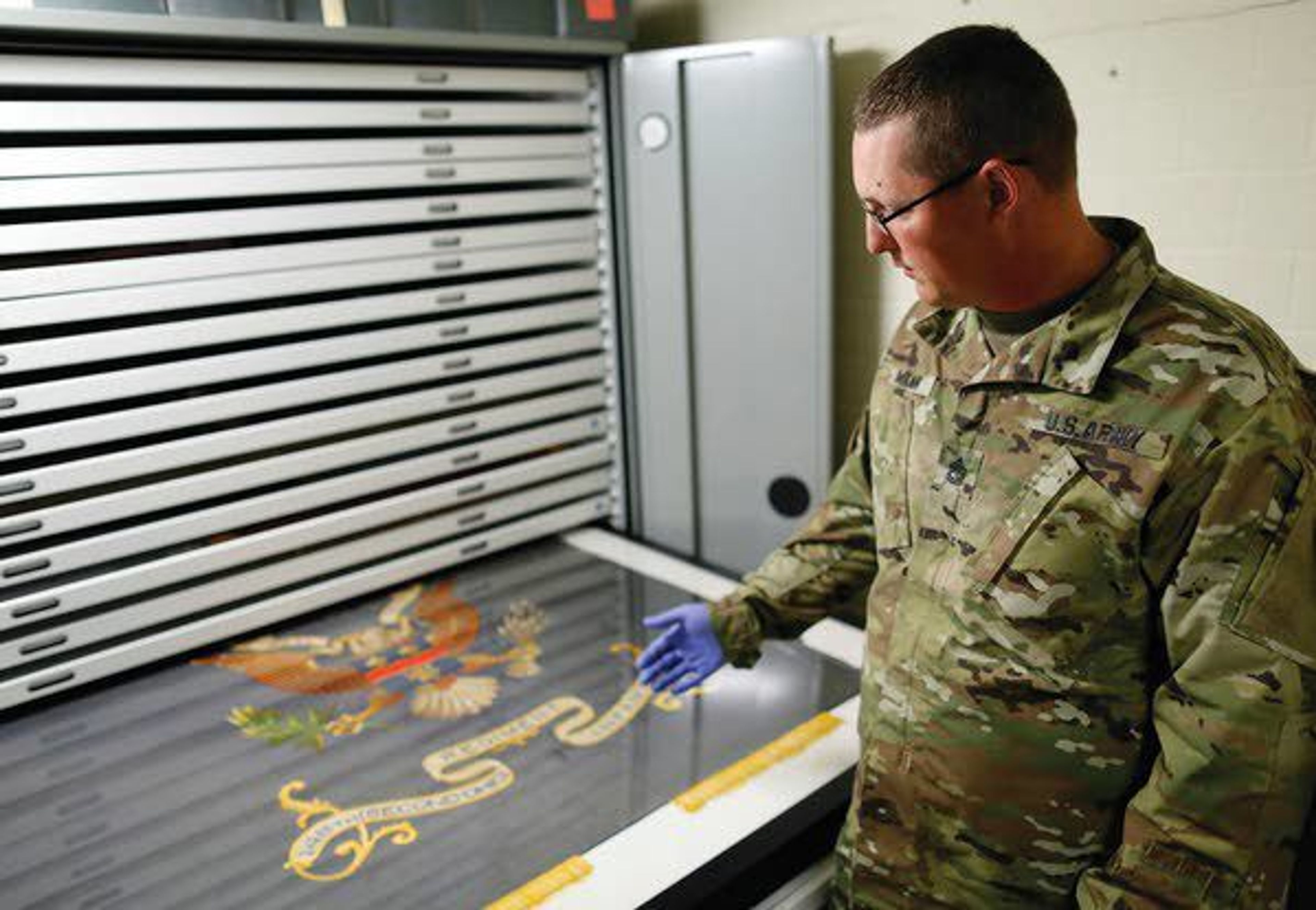 Sgt. 1st Class Josh Mann, Ohio Army National Guard historian, looks at a Civil War battle flag from the 148th Infantry Regiment inside the Beightler Armory on July 17 in Columbus, Ohio.