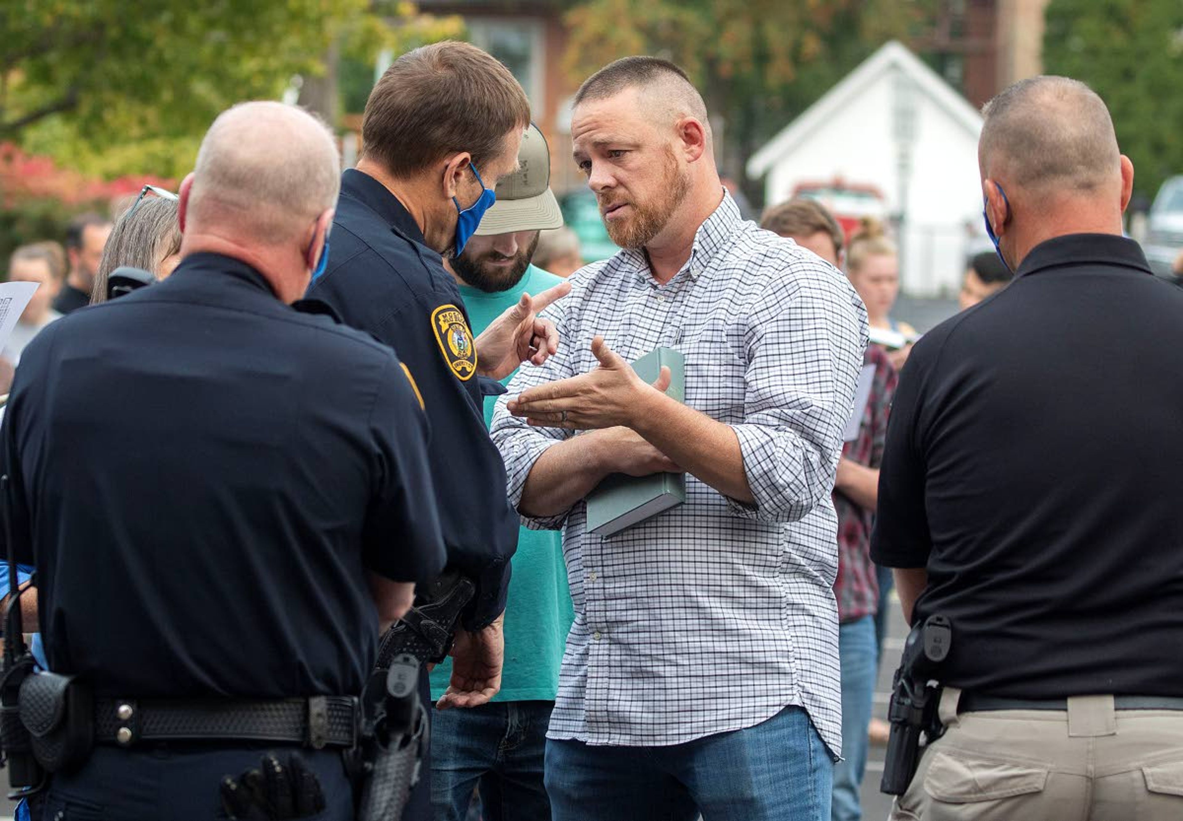 Gabe Rench, center, talks with Moscow police Capt. Will Krasselt before being arrested during a “flash psalm sing” organized by Christ Church on Wednesday outside Moscow City Hall. Rench is running against Tom Lamar for a seat on the Latah County Commission.