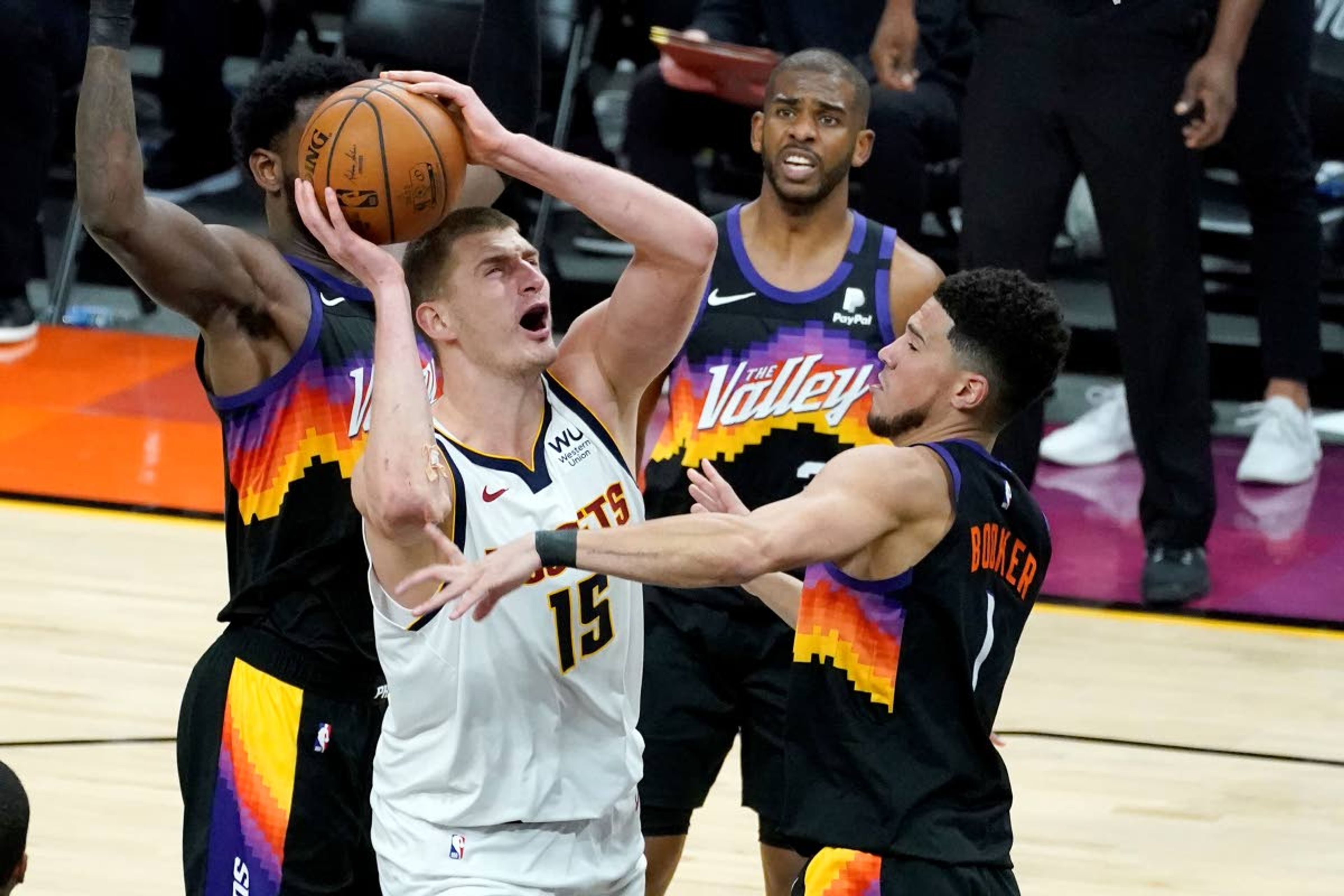 Denver Nuggets center Nikola Jokic (15) shoots over Phoenix Suns guard Devin Booker (1) during Game 1 of an NBA basketball second-round playoff series, Monday, June 7, 2021, in Phoenix. (AP Photo/Matt York)