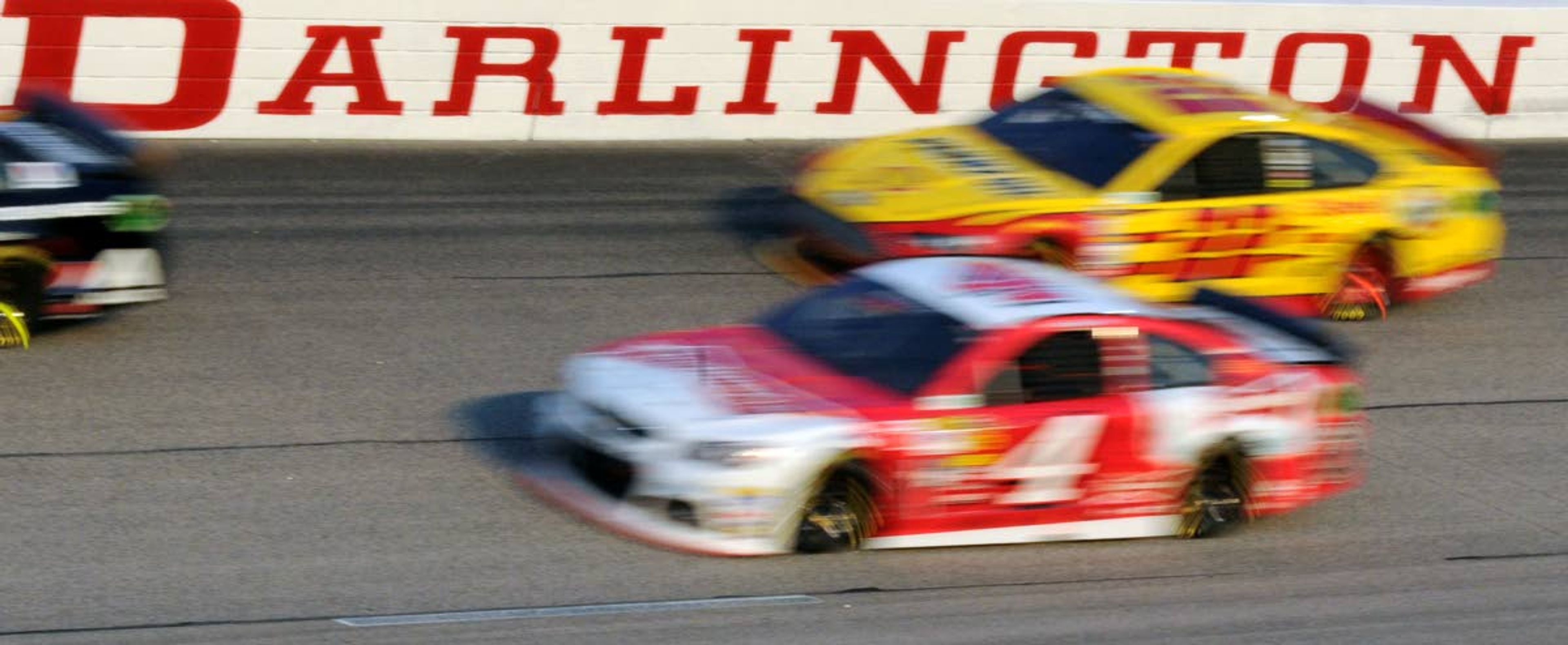 FILE - In this April 12, 2014, file photo, Kevin Harvick (4) and Joey Logano (22) race during a NASCAR Sprint Cup series auto race at Darlington Raceway in Darlington, S.C. NASCAR will get its season back on track starting May 17 at Darlington Raceway in South Carolina without spectators, and the premier Cup Series plans to race four times in 10 days at a pair of iconic tracks. The revised schedule released Thursday, April 30, 2020, goes only through May and has a pair of Wednesday races — fulfilling fans longtime plea for midweek events. (AP Photo/Mike McCarn, File)