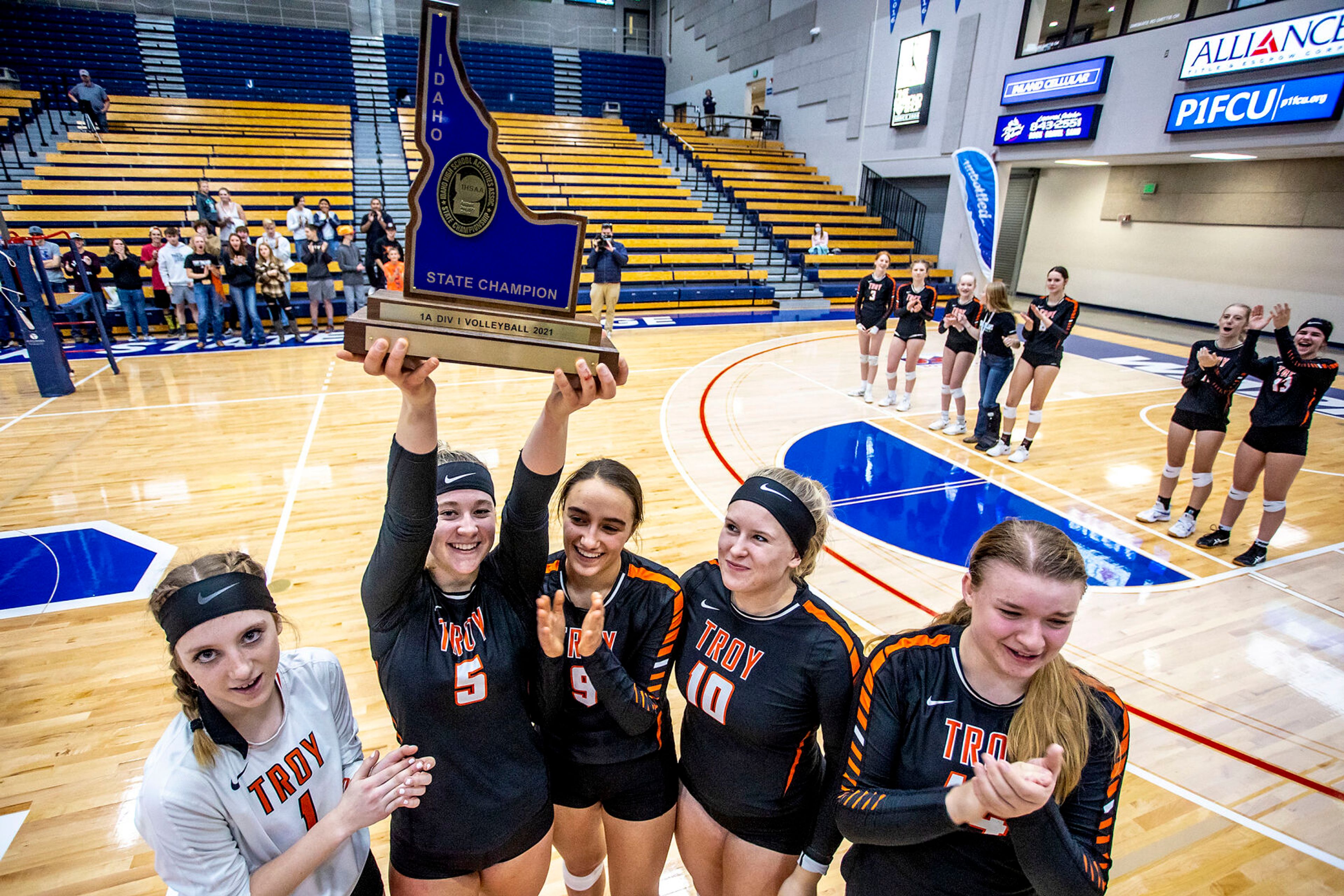 Troy’s Morgan Blazzard holds their state champion title high in the air at the Lewis-Clark State College Athletic Center on Saturday. Troy defeated Grace in three sets to become the 1A DI state champions.