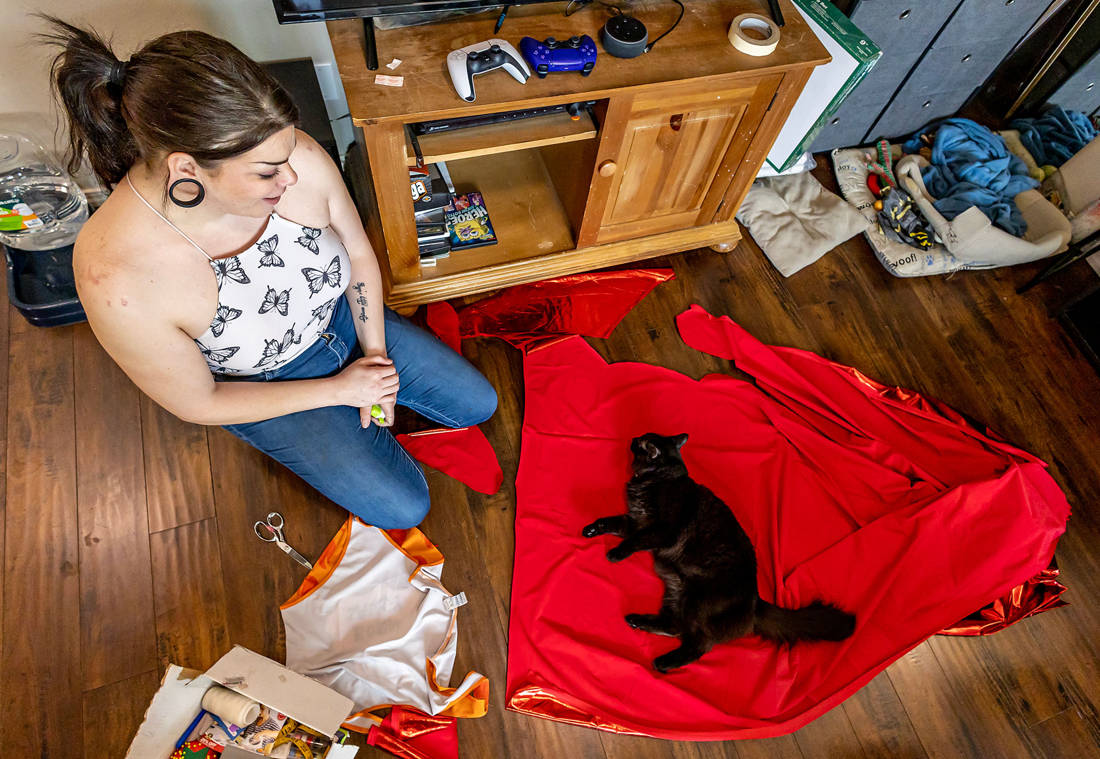 One of Wabaunsee’s cats very cutely interprets her as Wabaunsee starts to cut pieces of fabric for her drag outfits March 13 at her home in Pasco, Wash.