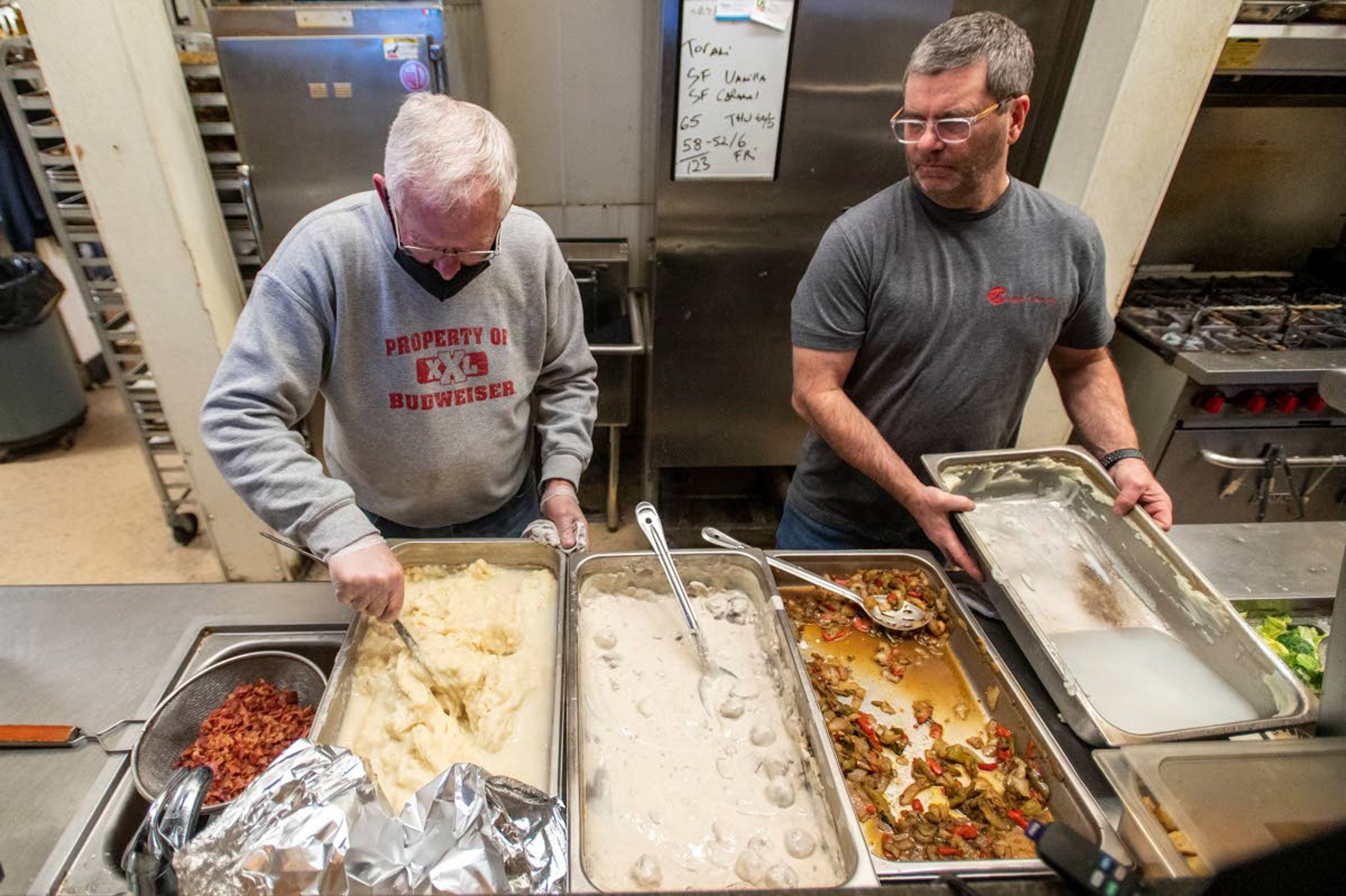 Volunteer Steve Copeland, left, and Oak on Main owner Frank Maryott dish meals containing mashed potatoes, meatballs and vegetables for the Feeding Our Friends program Tuesday night at the restaurant in Pullman.