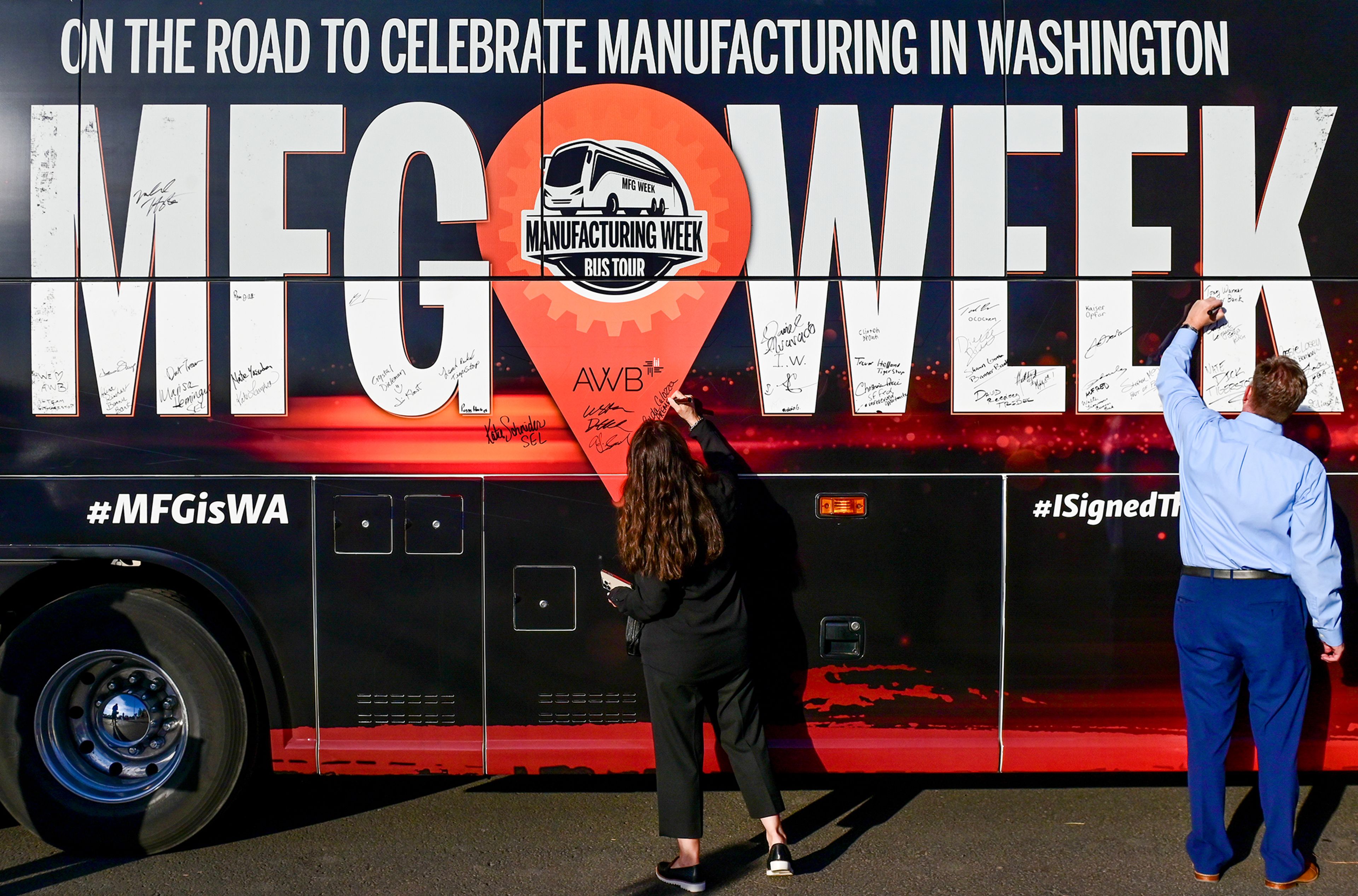 Schweitzer Engineering Laboratories employee-owners sign the Association of Washington Business Manufacturing Week bus Thursday at its stop at SEL in Pullman.