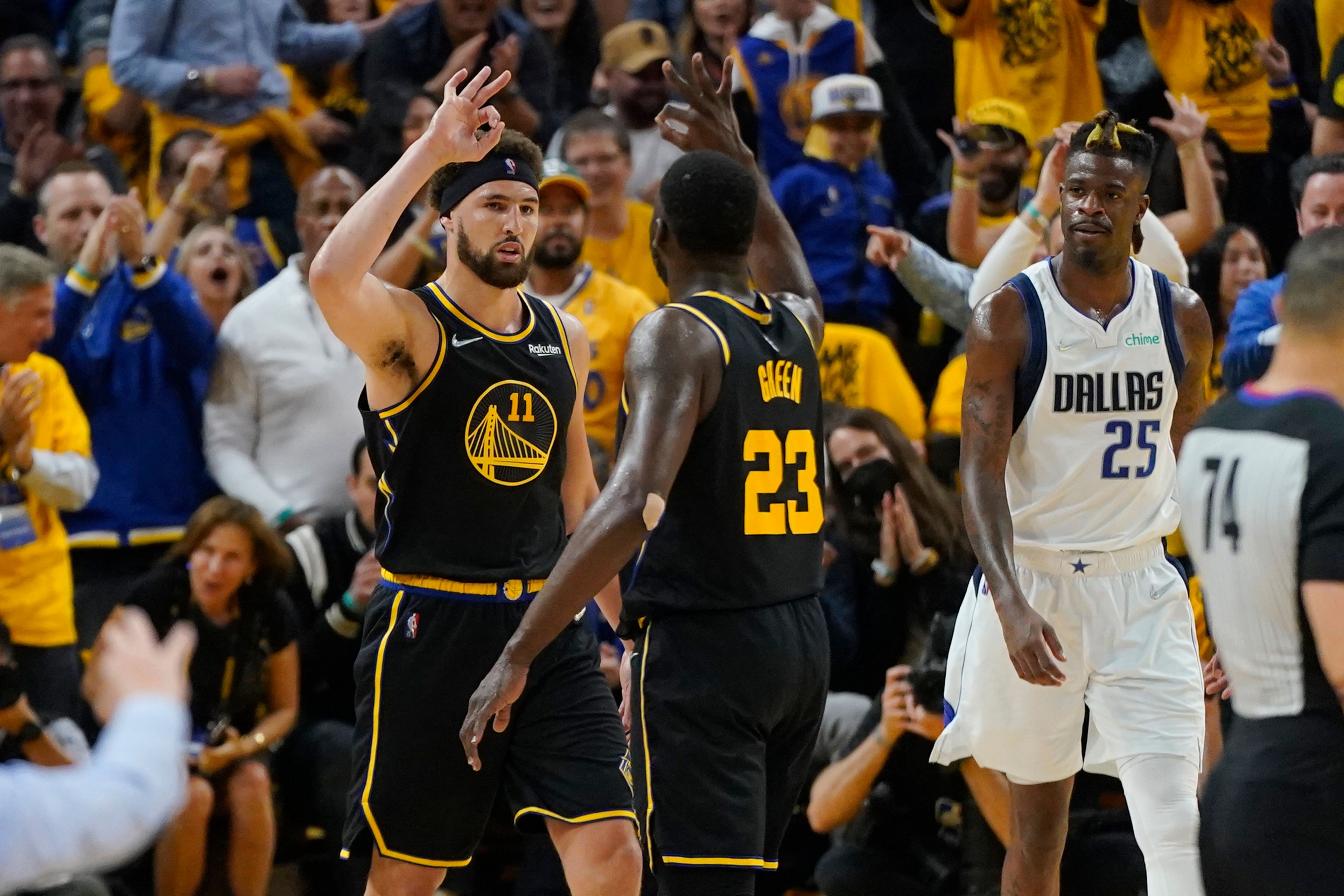 Golden State Warriors guard Klay Thompson (11) celebrates his basket with forward Draymond Green (23), next to Dallas Mavericks forward Reggie Bullock (25) during the first half in Game 5 of the NBA basketball playoffs Western Conference finals in San Francisco, Thursday, May 26, 2022. (AP Photo/Jeff Chiu)