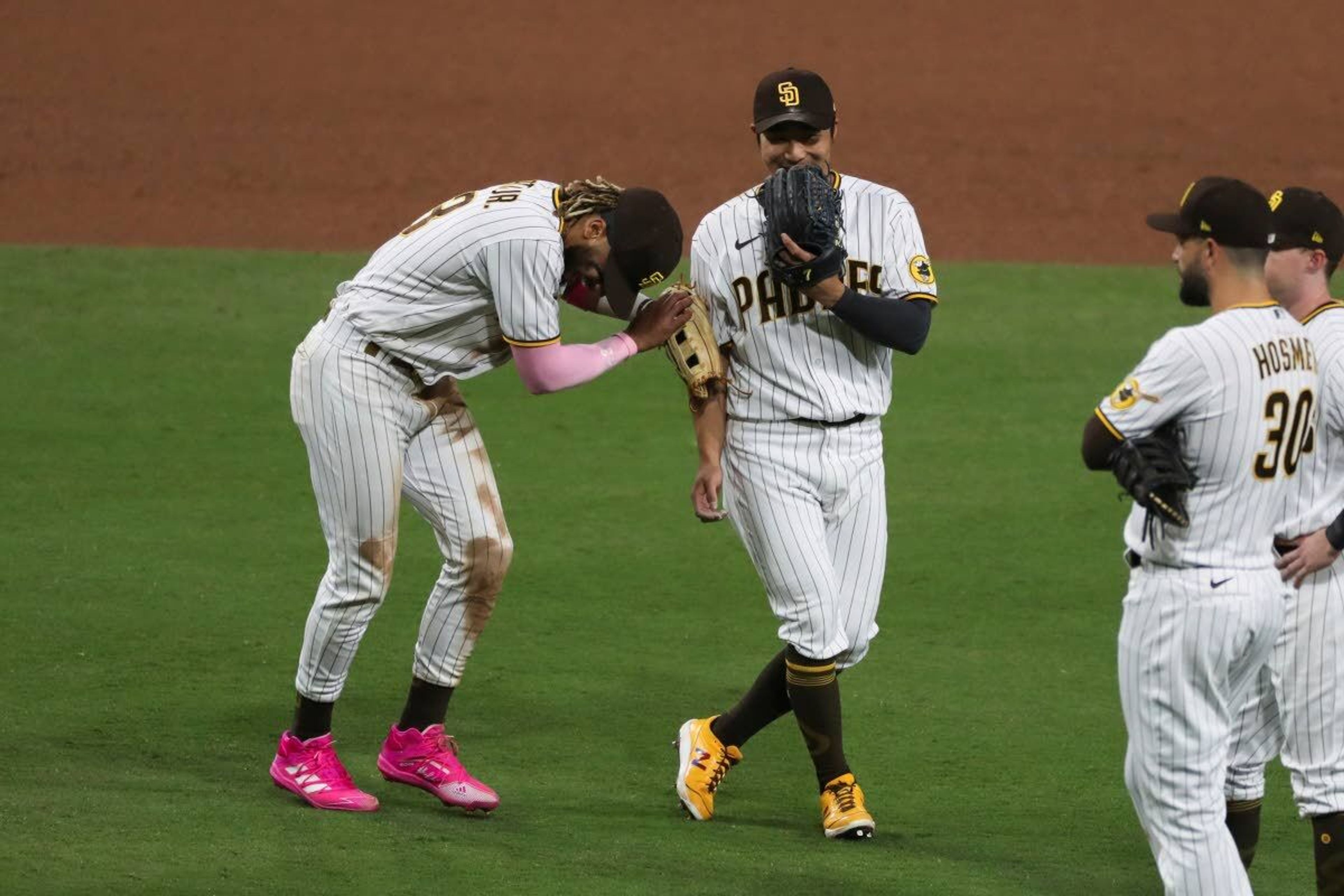 San Diego Padres shortstop Fernando Tatis Jr., left, laughs with third baseman Ha-Seong Kim during a pitching change in the ninth inning of the team's baseball game against the Seattle Mariners on Saturday, May 22, 2021, in San Diego. (AP Photo/Derrick Tuskan)