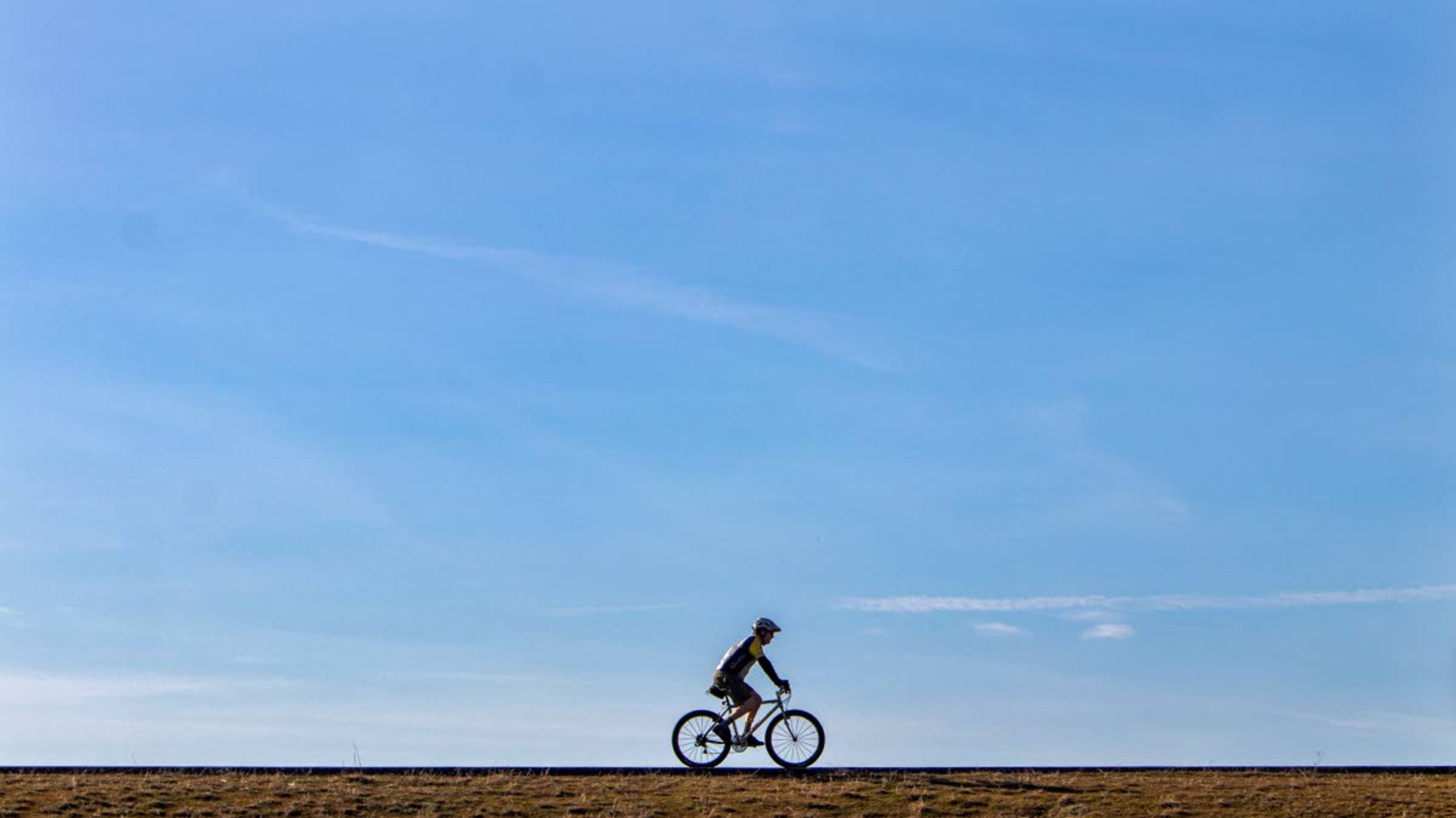 A man peddles his bike along the Lewiston Levee Parkway Trial on Wednesday afternoon.