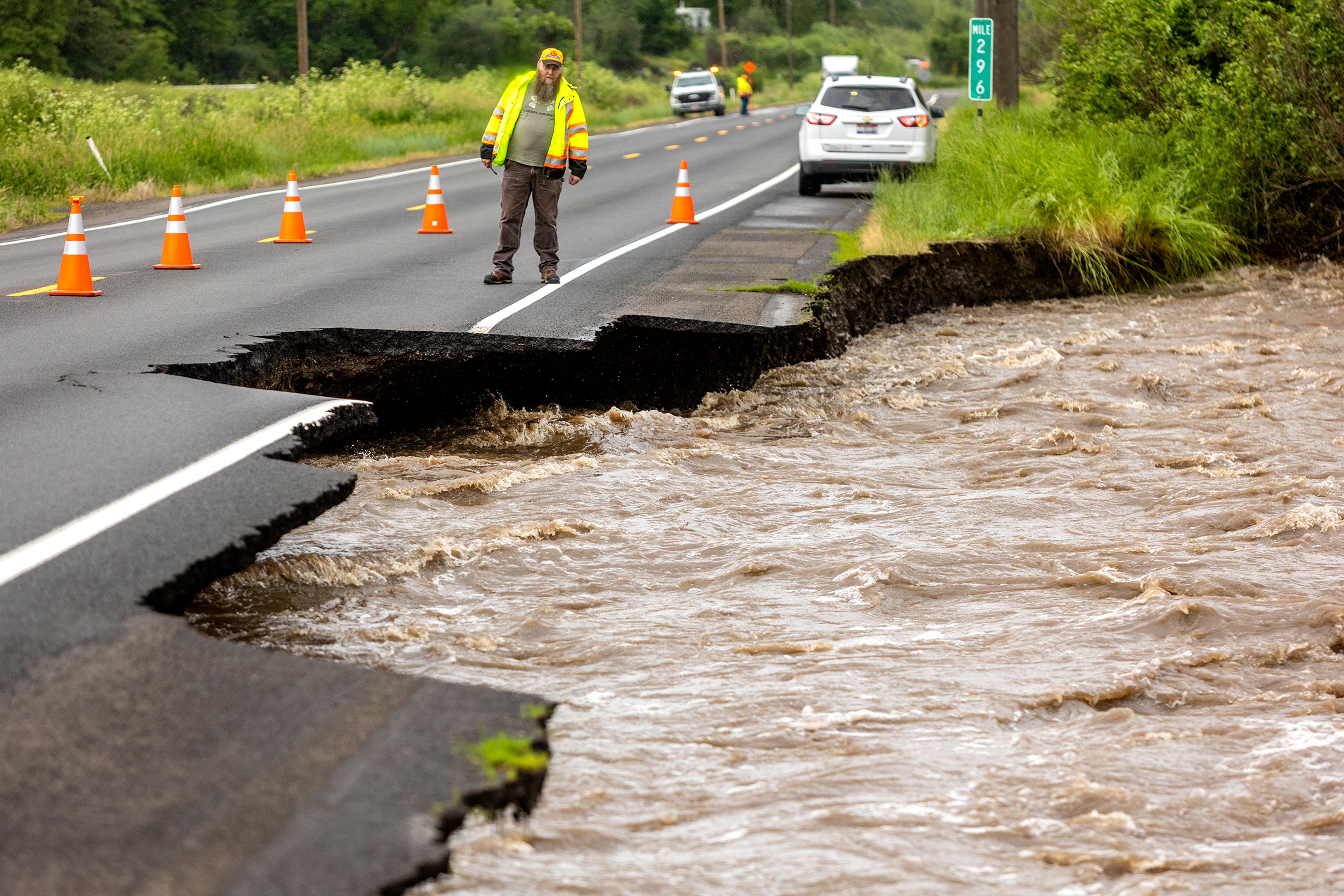 A worker looks to where water from Lapwai Creek is eroding U.S. Highway 95. The road became one lane of travel on Monday morning.