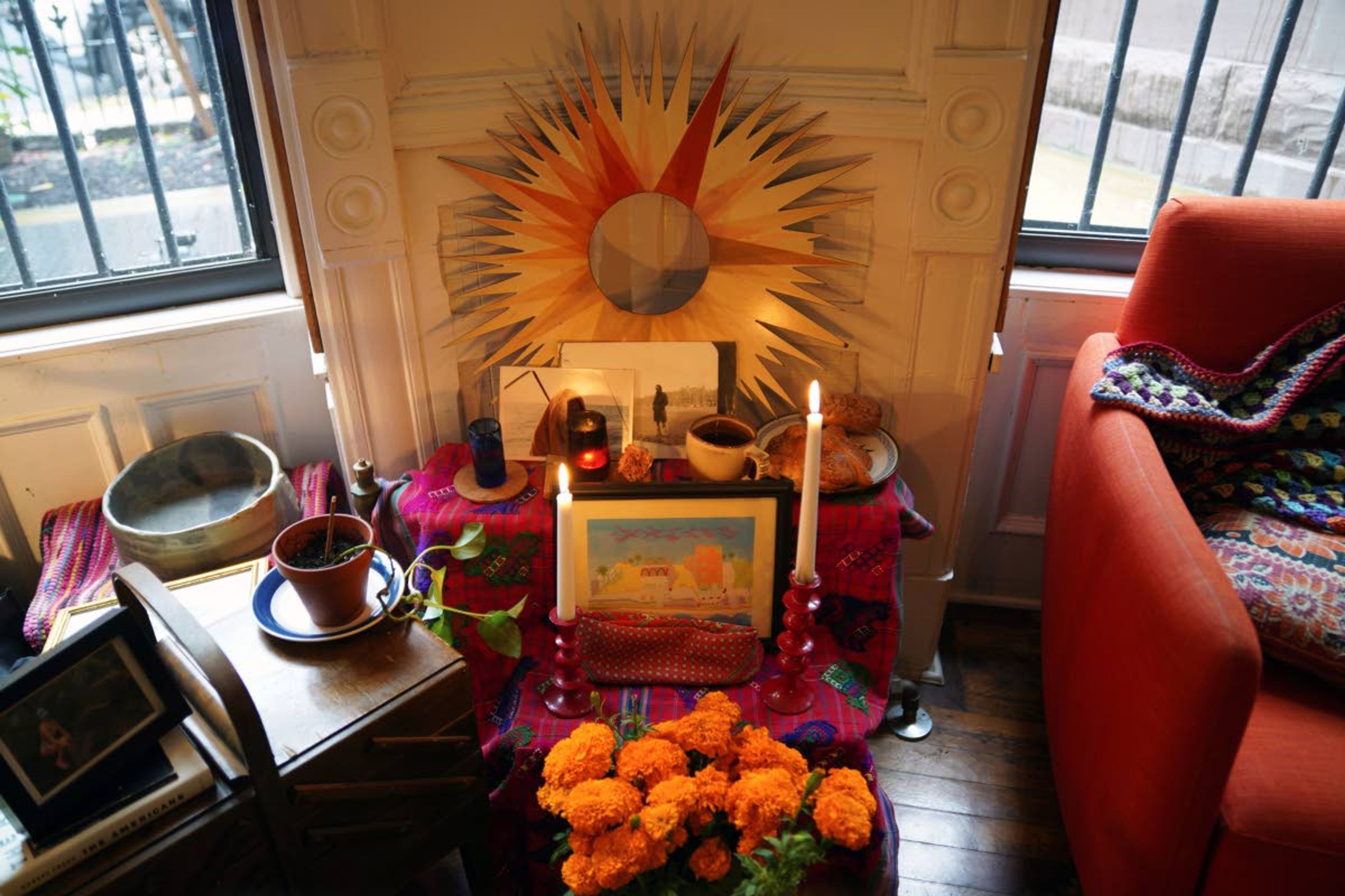 A Day of the Dead altar decorated with photographs, candles, marigolds and favorite items and foods sits in Sebastian Diaz Aguirre's living room in the Brooklyn borough of New York, Wednesday, Oct. 28, 2020. "It feels extremely comforting. I do feel I have a connection with my dad," said Diaz Aguirre, who set up the altar in remembrance of his father. (AP Photo/Emily Leshner)