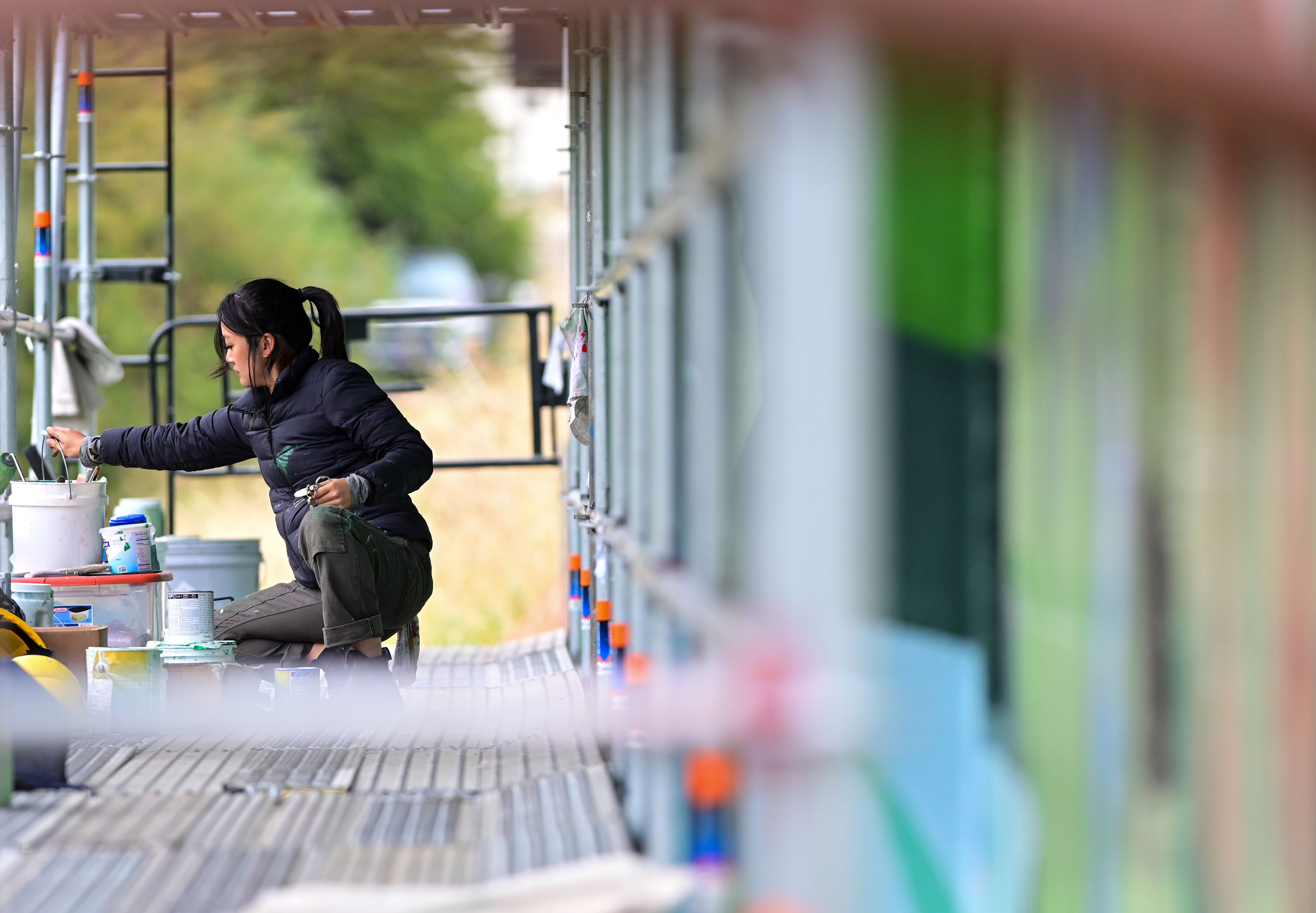 Tori Shao, an artist and landscape architect, grabs more paint while working on a new mural in downtown Pullman.