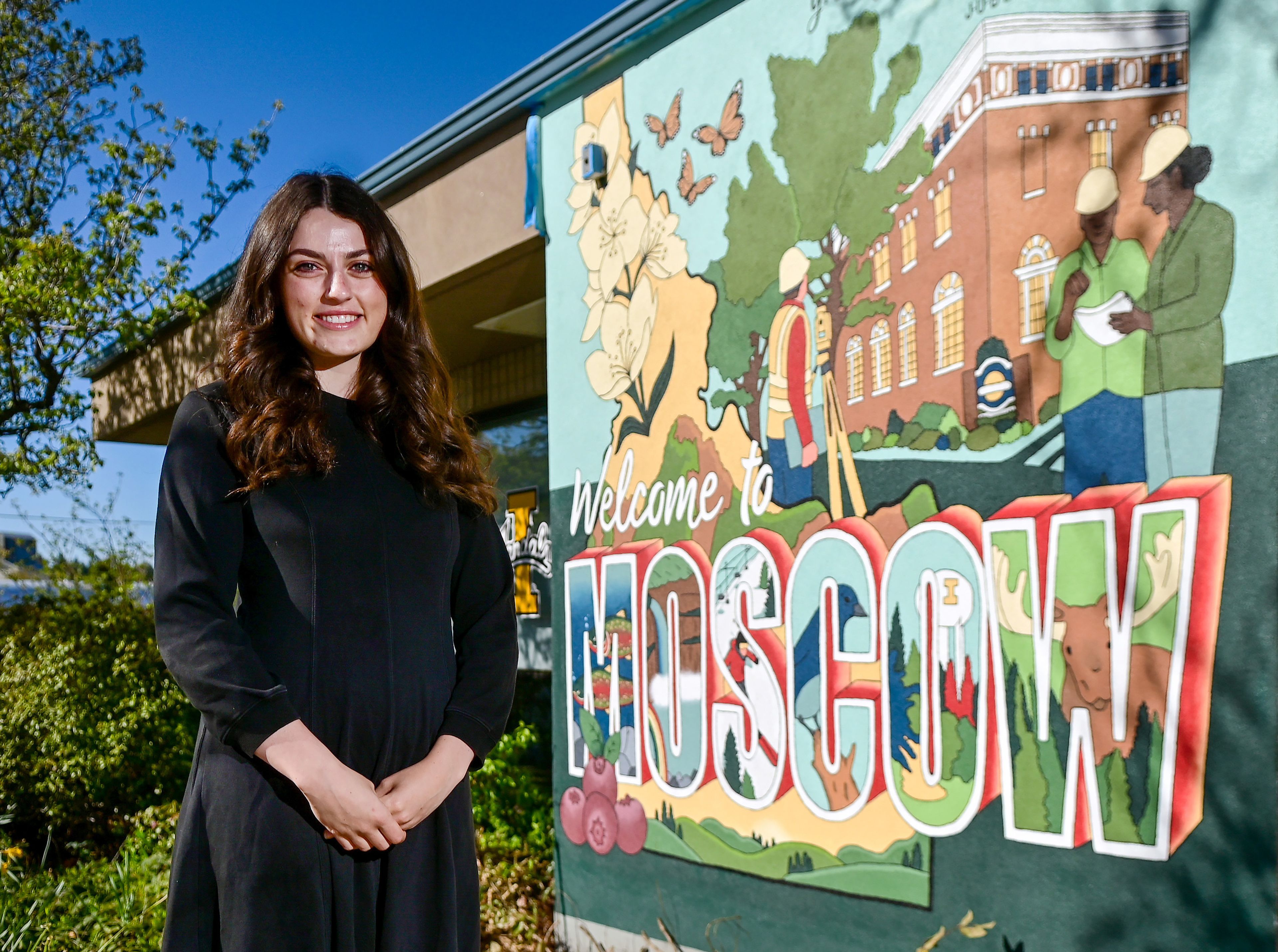 University of Idaho graduate student Madelynn Gregoire stands next to a Moscow-themed mural she painted on the side of the J-U-B Engineers building in downtown Moscow on Monday.