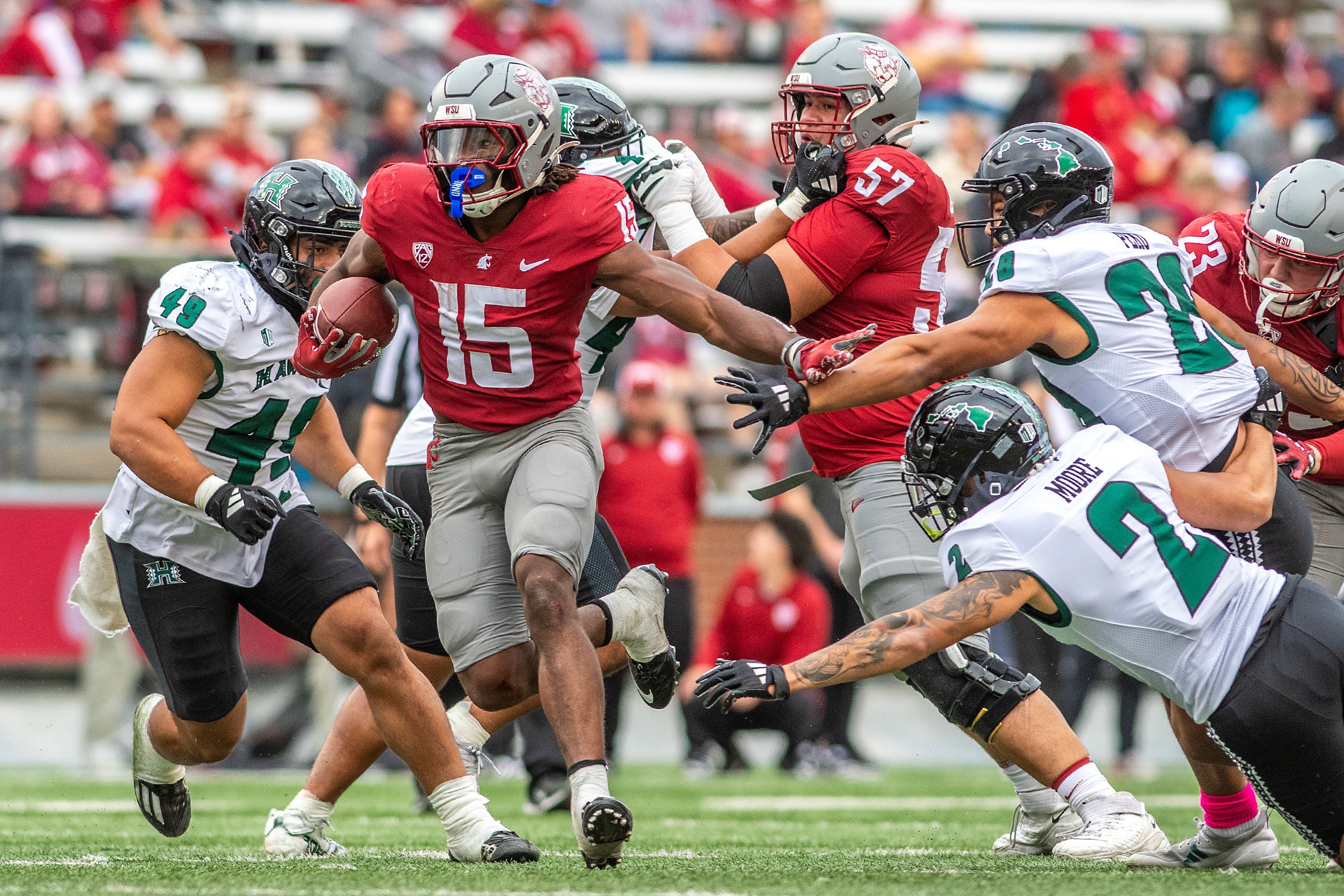 Washington State running back Djouvensky Schlenbaker avoids a tackle from Hawaii defensive back Kona Moore and Hawaii defensive lineman Vaifanua Peko in a college football game on Saturday at Gesa Field in Pullman.,