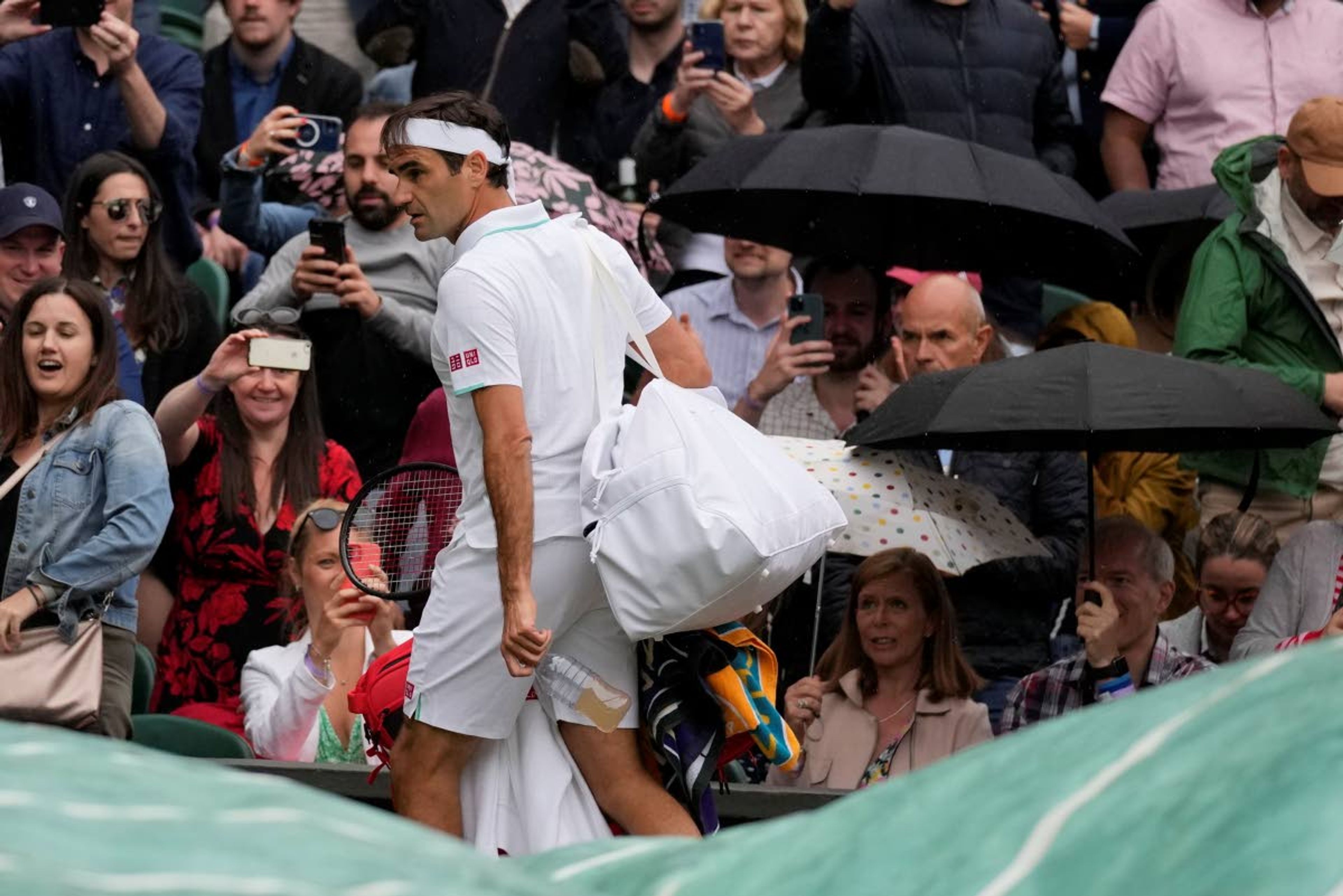 Switzerland's Roger Federer leaves the court as rain delays play during the men's singles fourth round match against Italy's Lorenzo Sonego on day seven of the Wimbledon Tennis Championships in London, Monday, July 5, 2021. (AP Photo/Kirsty Wigglesworth)