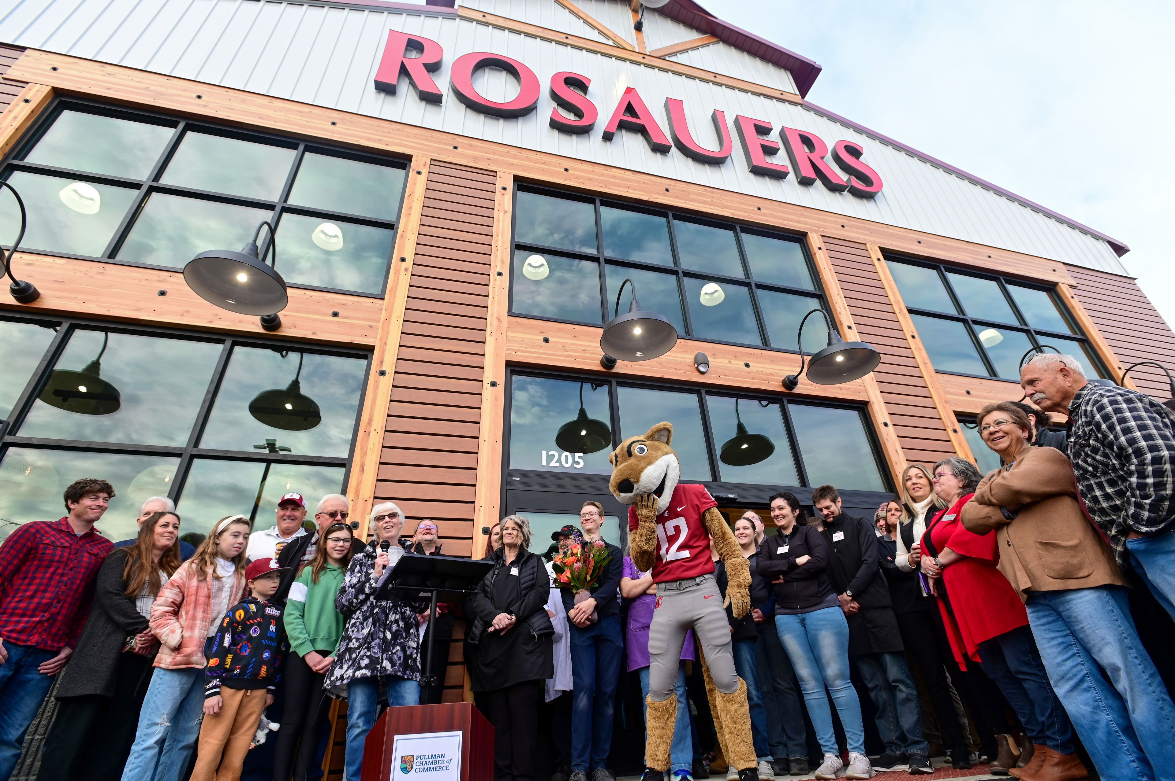 The crowd laughs in response to a joke by Dede Boone, center, as she speaks at a grand opening event for the new Rosauers along North Grand Avenue in Pullman on Wednesday.