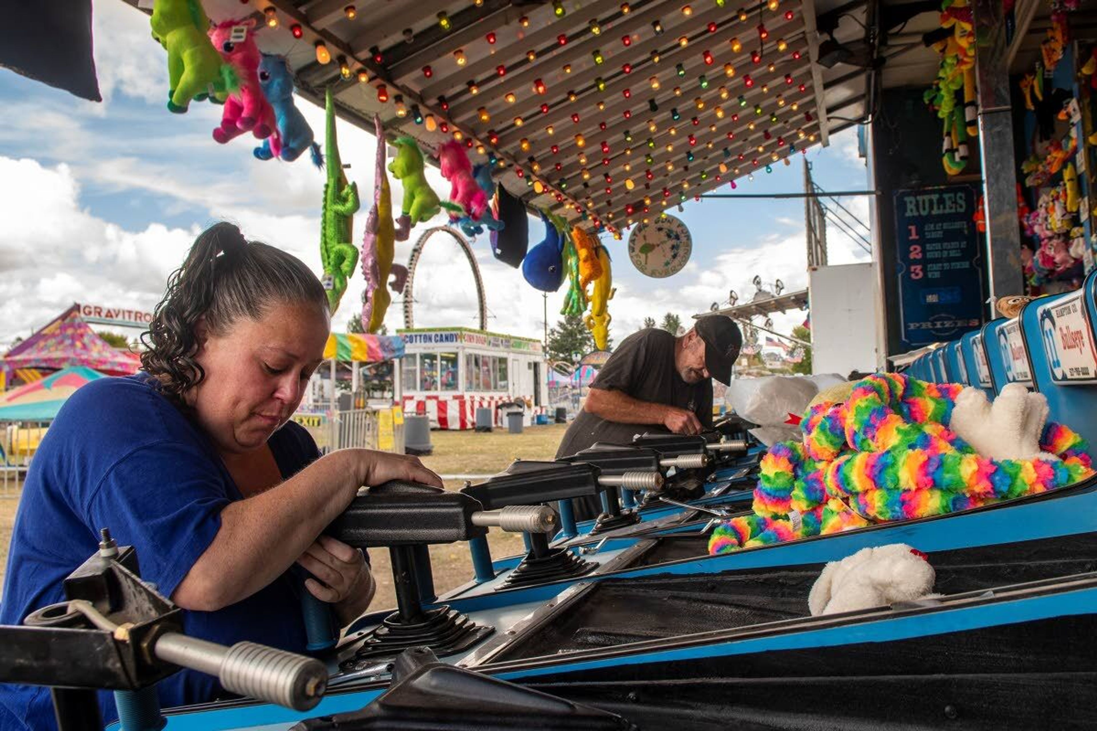 Jennifer Columbus, left, and Thomas Hamm, of Paradise Amusements carnival, inspect the water guns at the bull's-eye blaster “water race” as they prepare for the Latah County Fair at the Latah County Fairgrounds on Wednesday afternoon. “I love how excited the kids get. You can’t fake that kind of enjoyment,” said Columbus, who started working at the carnival when she was 18.