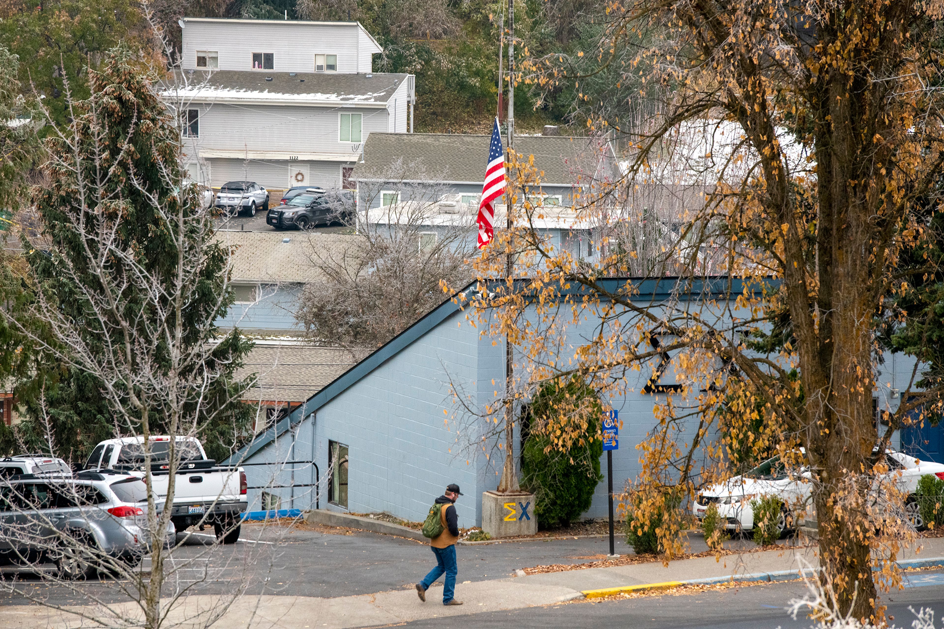 An American flag flies at half-staff in front of the University of Idaho Sigma Chi fraternity house where Ethan Chapin was a member. Chapin was one of four deceased victims involved in a homicide investigation at the house seen behind the fraternity.