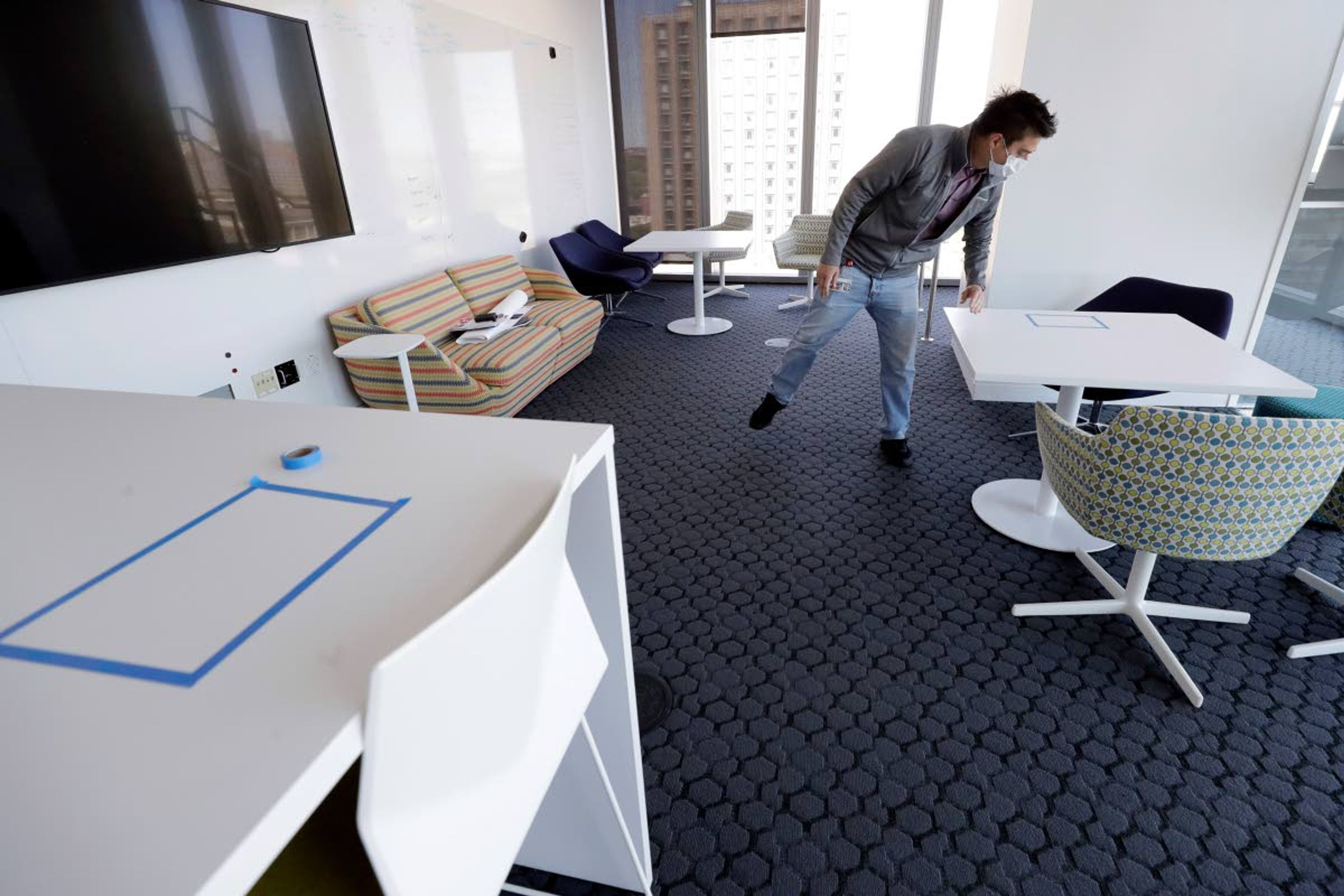 Kevin Gonzales, director of operations at the Rajen Kilachand Center for Integrated Life Sciences and Engineering, at Boston University, arranges a room for its newly designated occupancy of three people on the school's campus, in Boston, Thursday, May 21, 2020. Boston University is among a growing number of universities making plans to bring students back to campus this fall, but with new measures meant to keep the coronavirus at bay. The room formerly had seating for over a dozen people. (AP Photo/Steven Senne)