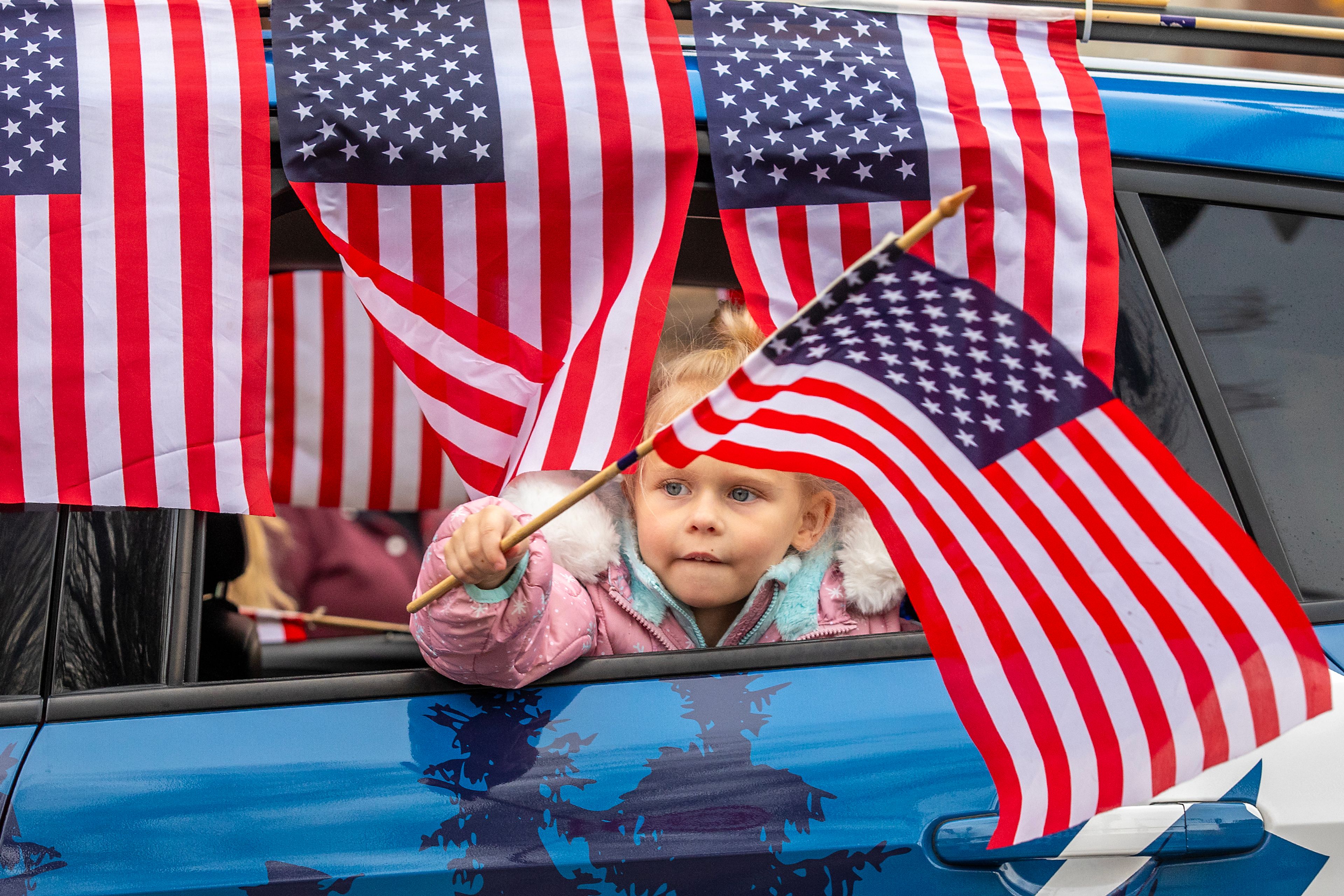 A girl waves an American flag while leaning out a car window Saturday at the Veteran’s Day Parade on Main Street in Lewiston.