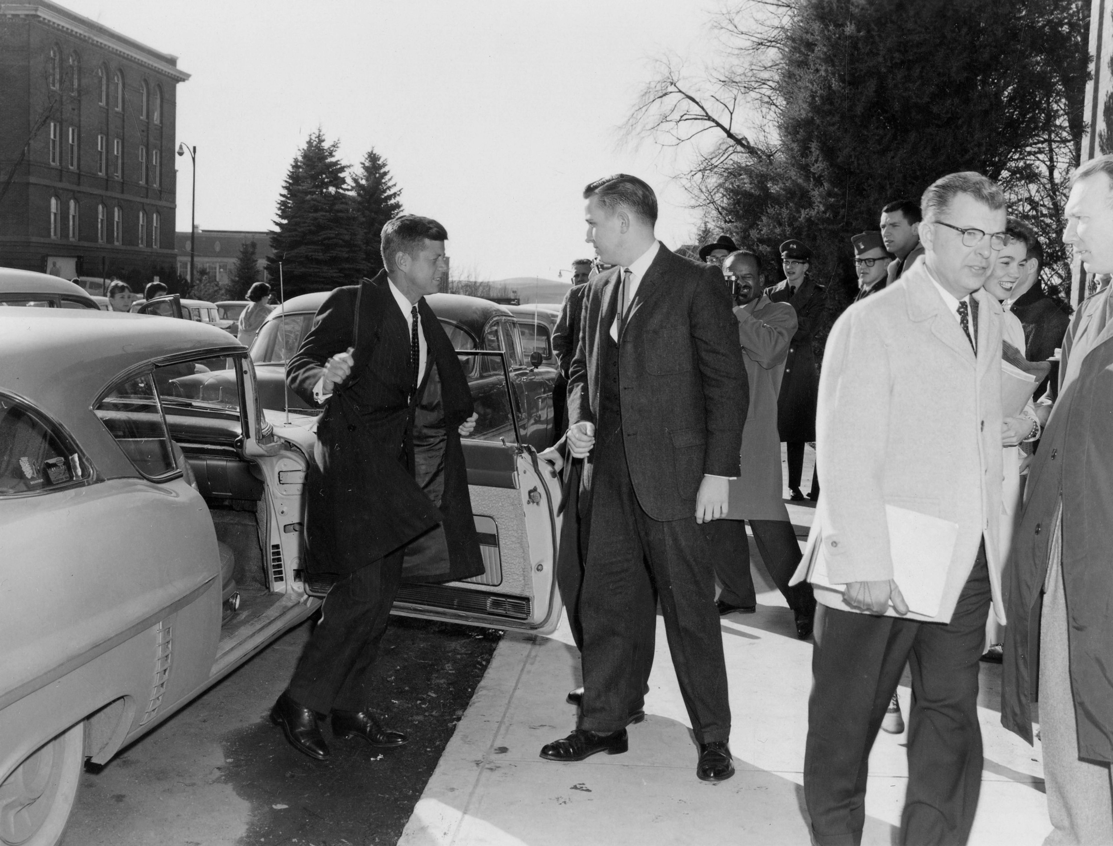 John F. Kennedy takes off his coat as he exits his car outside Bryan Hall on the Washington State University campus in Pullman.