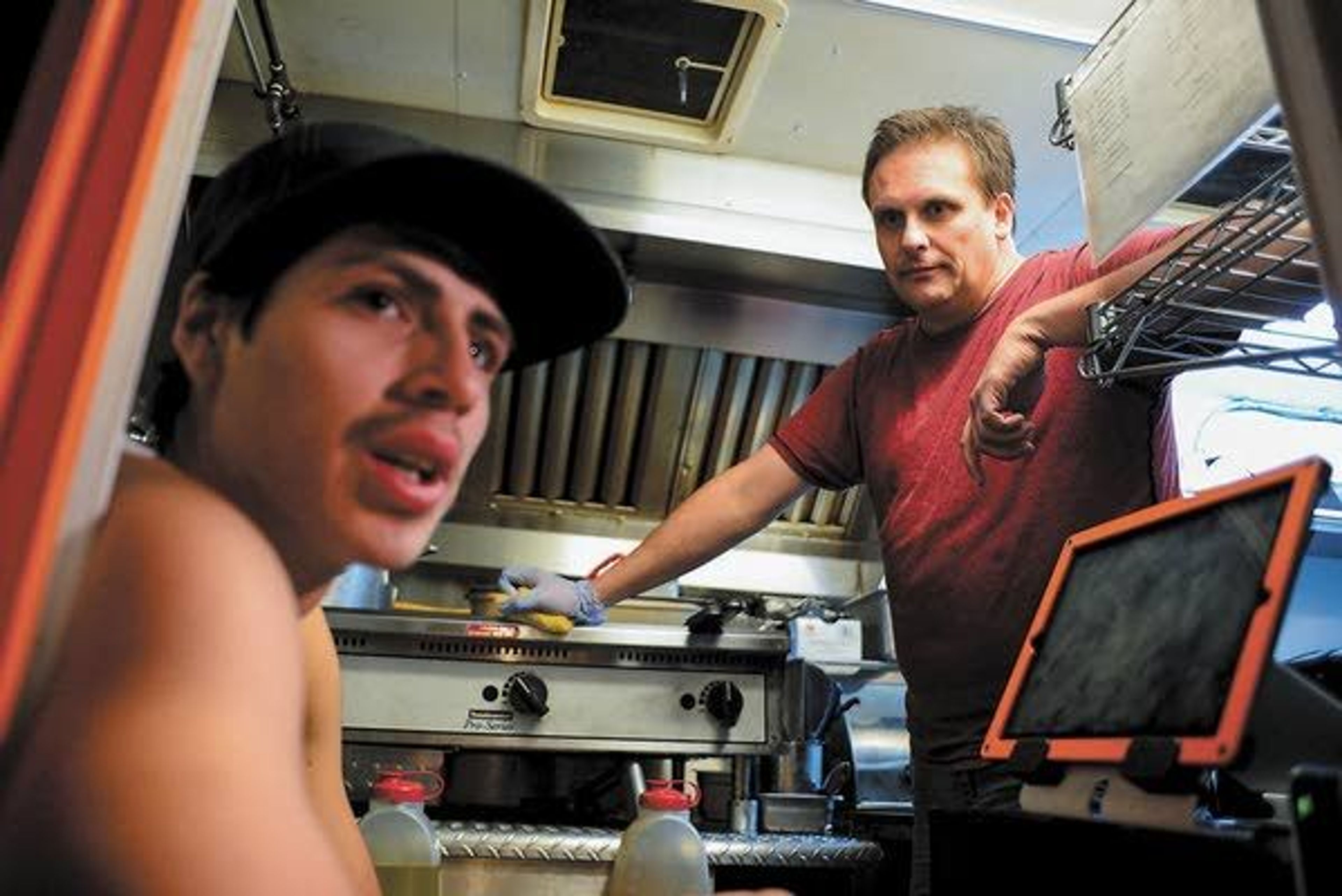 John Fletcher, Grub Truck owner (right), and cook Bernardo Arias (left) talk while waiting for customers late Thursday on Main Street in Moscow.