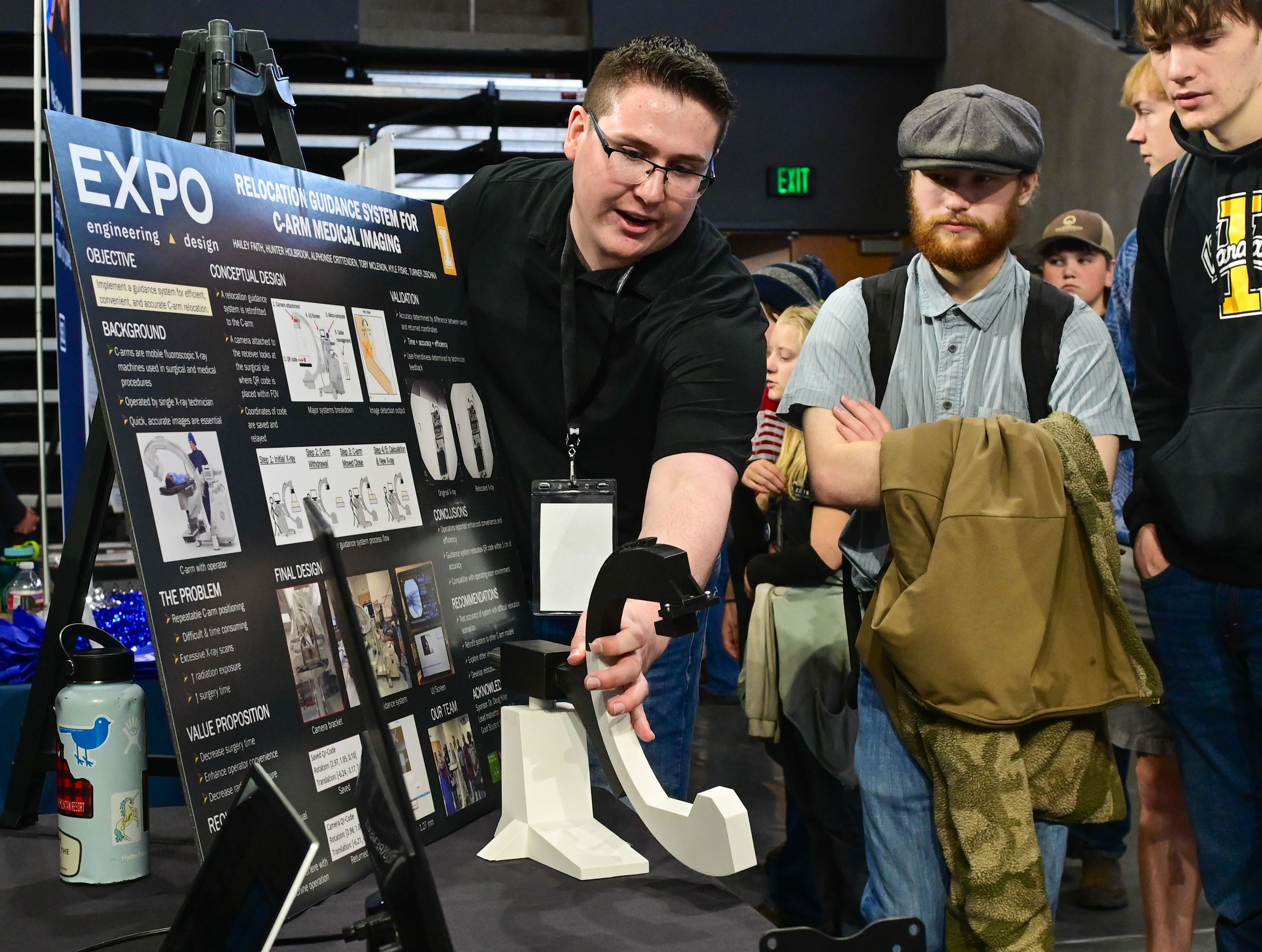 Kyle Fiske, left, a senior mechanical engineering student at the University of Idaho, holds a small C-Arm medical imaging model while explaining a relocation guidance system created for the machine at the Engineering Design EXPO capstone presentations in Moscow on Friday.