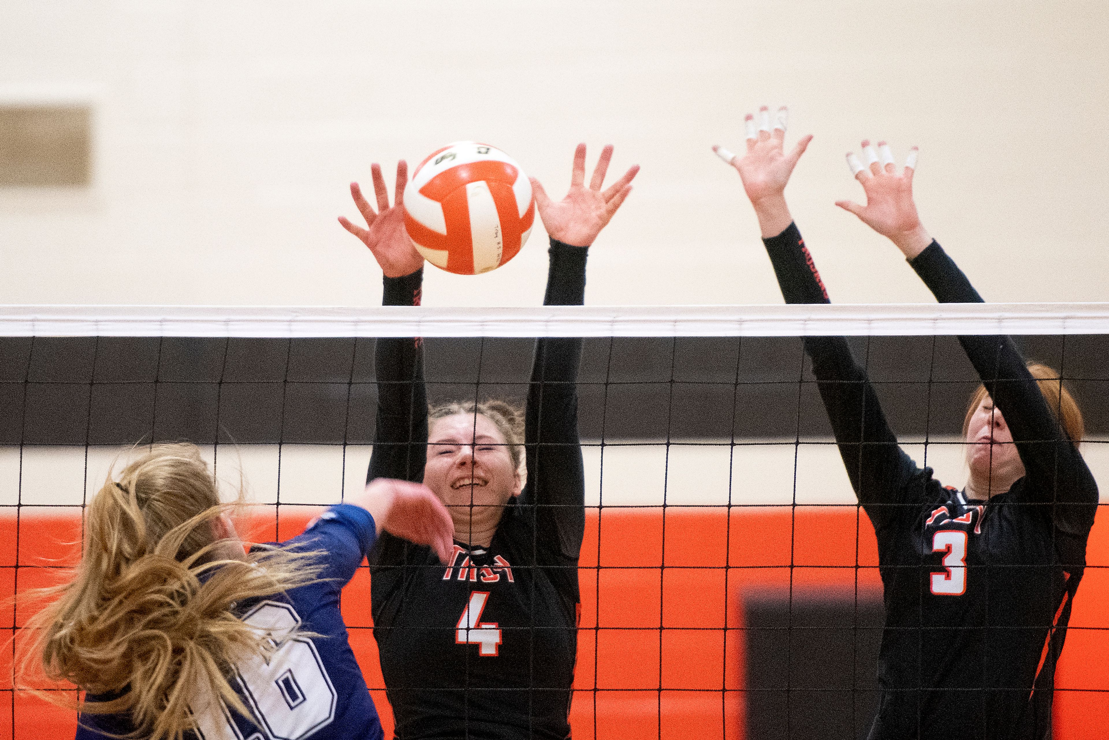 Troy’s Olivia Tyler (4) and Dericka Morgan (3) rise up to block a hit from Logos’ Signe Holloway (16) during a Whitepine League matchup at Troy High School on Tuesday.