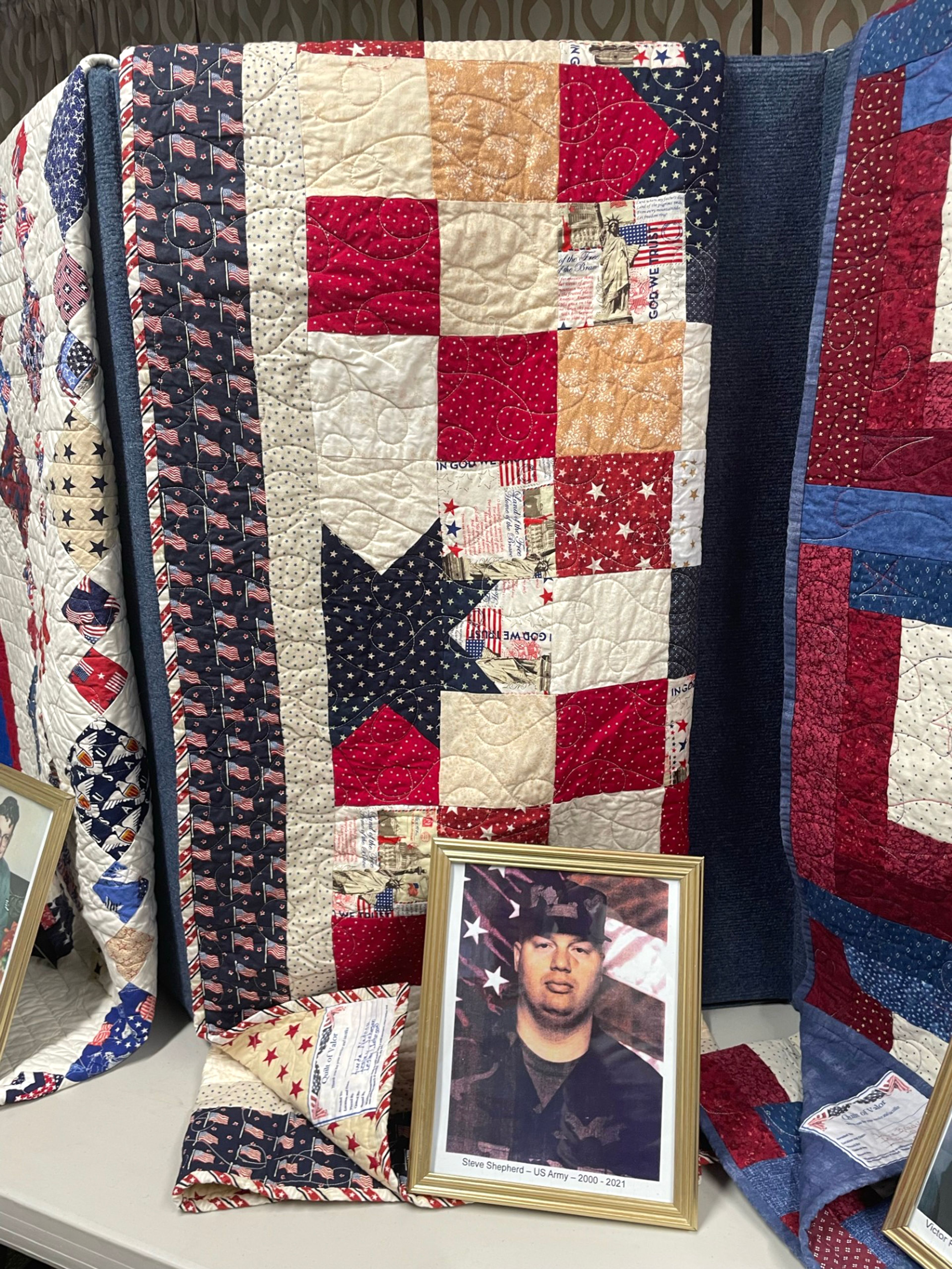 A picture of Steven Shepherd, Army, sits with his quilt of valor.