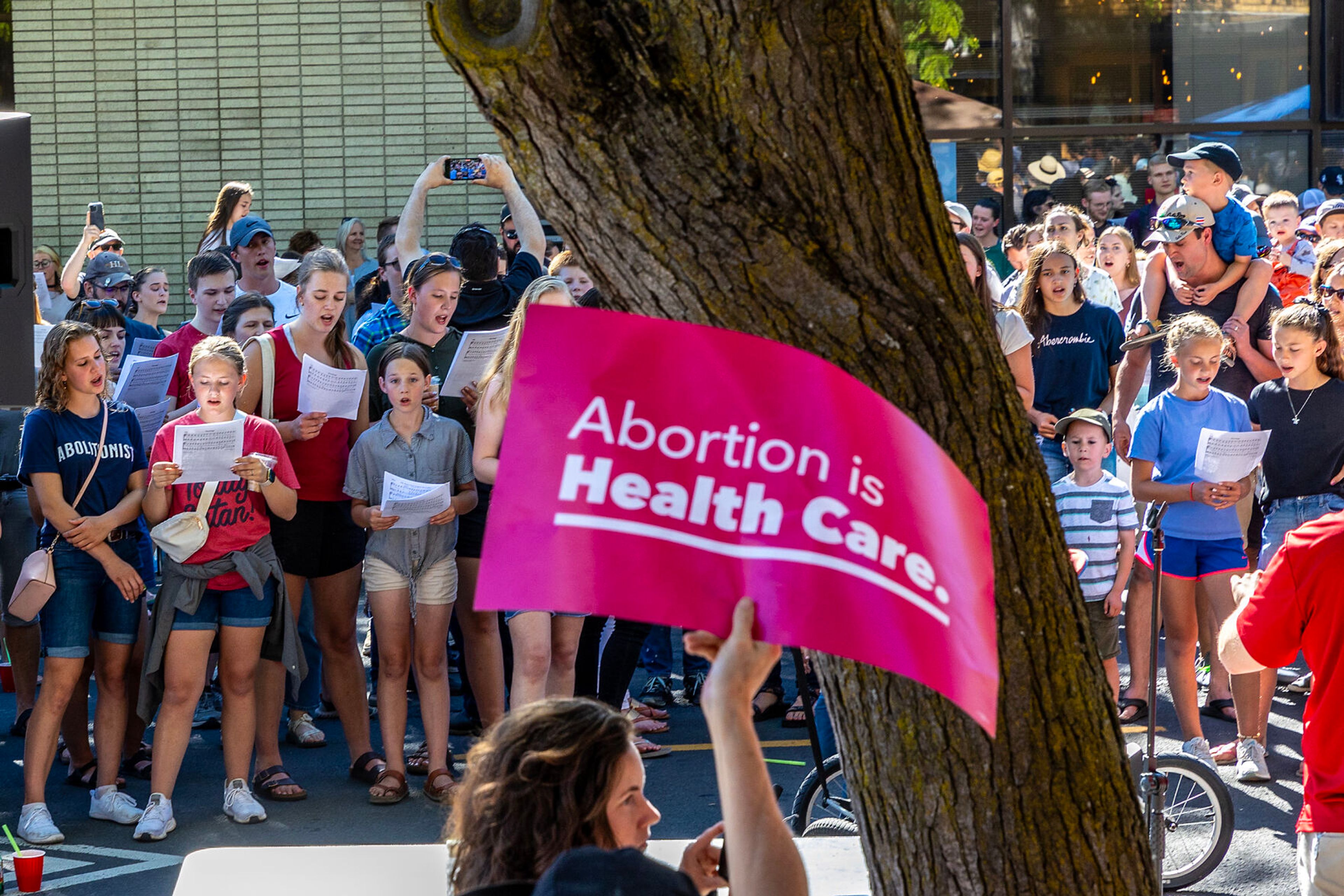 Christ Church members sing as counter protesters hold signs on the anniversary of the overturning of Roe v. Wade on Main Street Monday in Moscow.