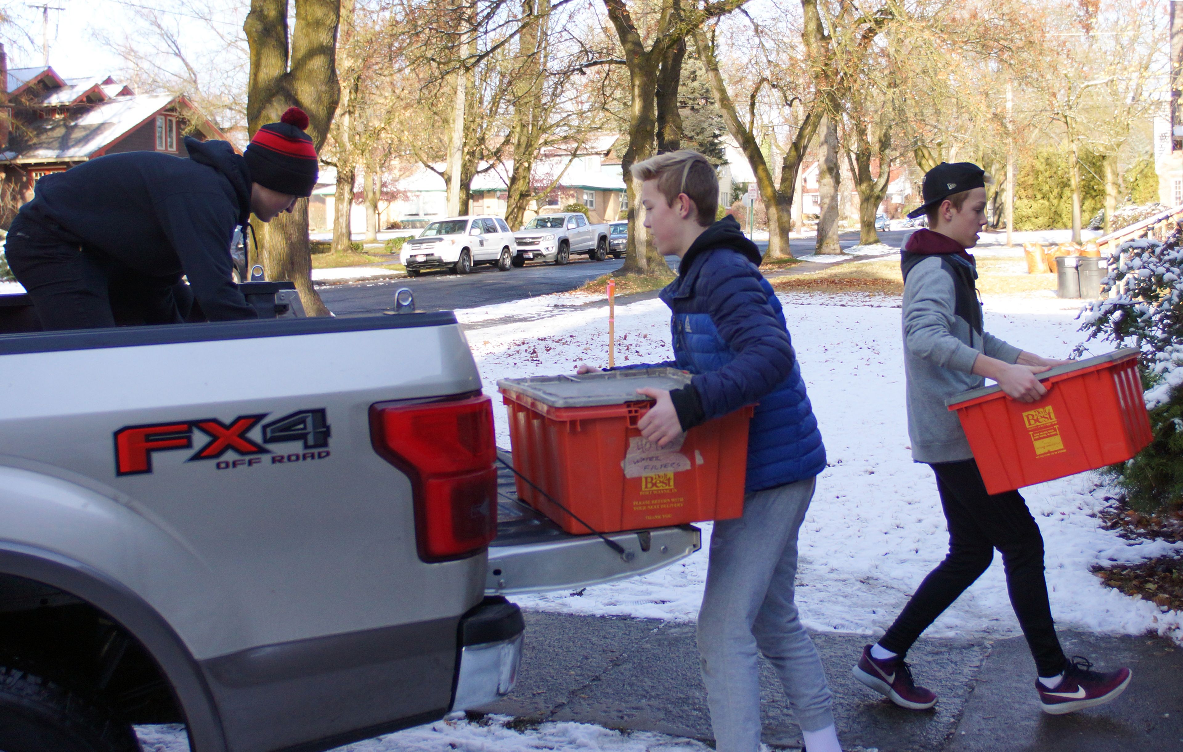 Michael Kiblen, left, Zac Skinner and Caleb Skinner unload crates of food from a pickup Saturday at the Moscow Food Bank during the 13th annual Palouse Cares Food Drive and Auctions.